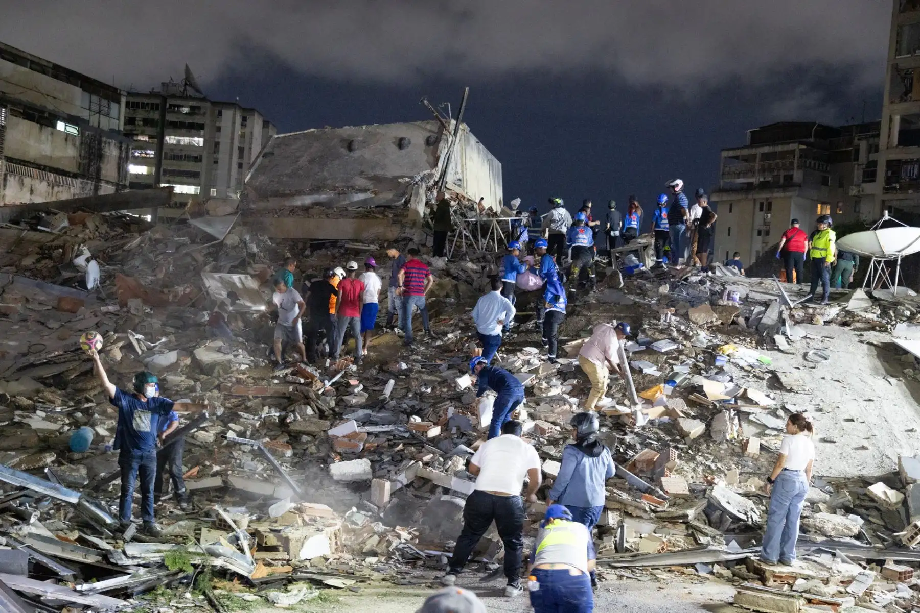Rescatistas y pobladores recorren los escombros de un edificio derrumbado en una de las zonas afectadas por los terremotos en Venezuela. Foto: ANDINA/AFP.