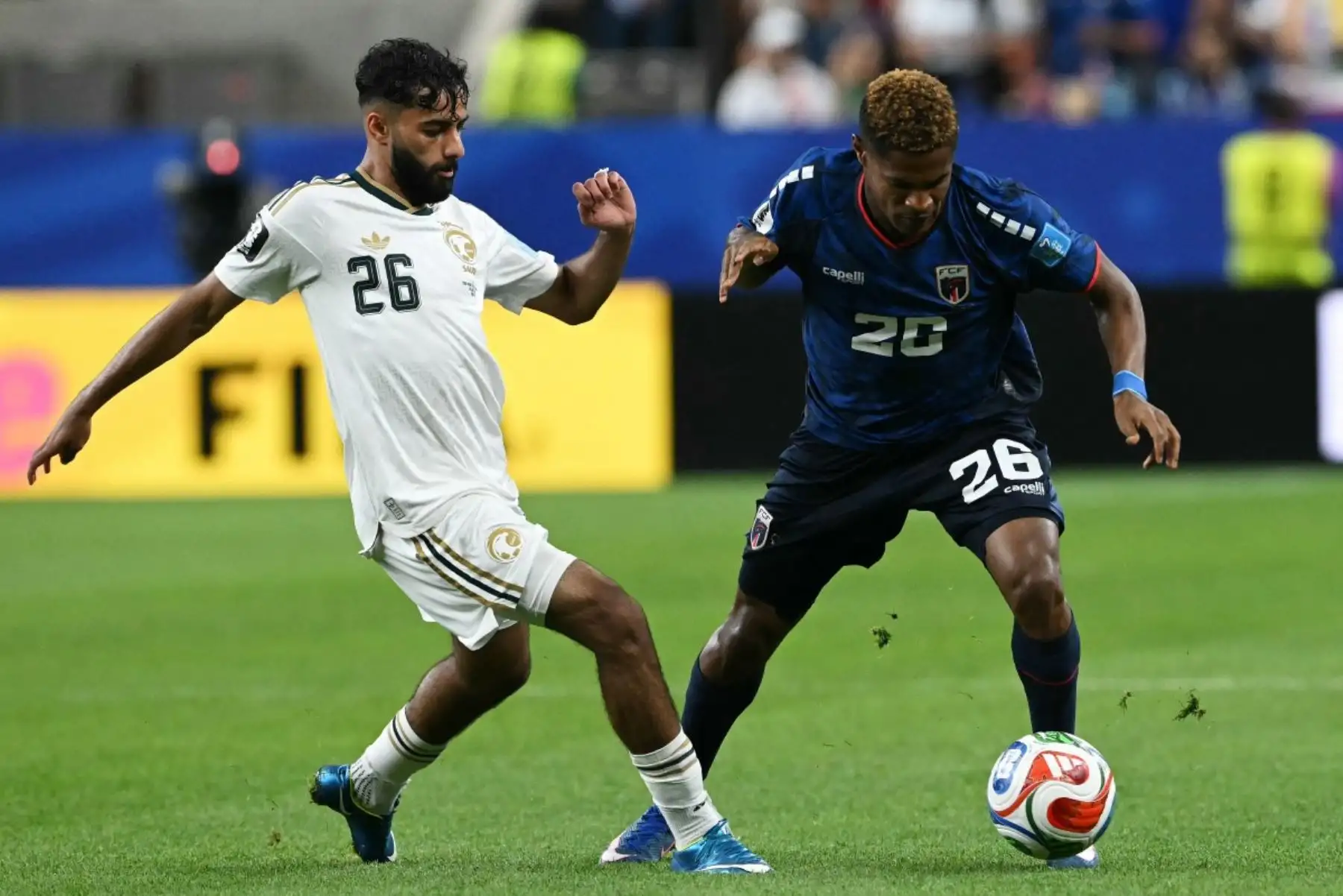 El defensa saudí Mohammed Abu Al-Shamat (izq.), número 26, y el delantero caboverdiano Helio Varela, número 26, disputan el balón durante el partido de fútbol del Grupo H de la Copa Mundial 2026 entre Cabo Verde y Arabia Saudí en el Estadio de Houston, el 26 de junio de 2026. (Foto de RONALDO SCHEMIDT / AFP)