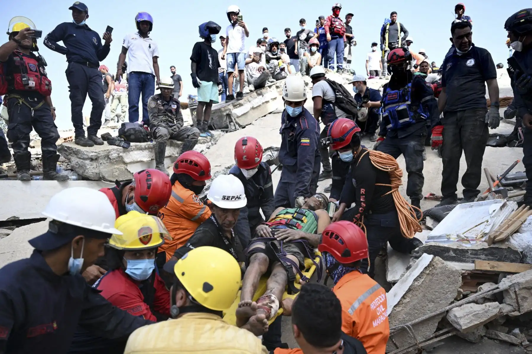 Miembros de Protección Civil y bomberos venezolanos rescatan a Patrick Vargas, de 21 años, de entre los escombros de un edificio derrumbado en Catia La Mar, La Guaira, Venezuela, el 26 de junio de 2026, tras los sismos. El número de muertos por los dos fuertes terremotos que devastaron Venezuela a principios de esta semana ascendió a 920 el 26 de junio, según informó el presidente de la Asamblea Nacional, Jorge Rodríguez. Foto: AFP
