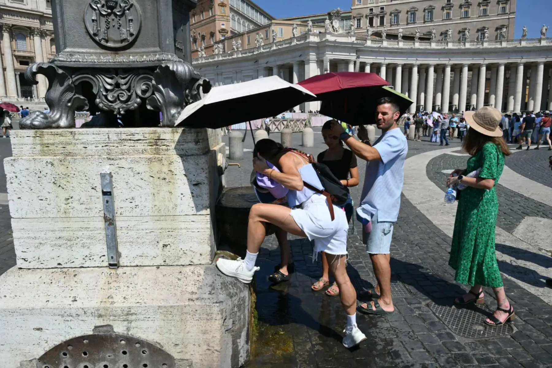 Varias personas se refrescan en una fuente mientras esperan el rezo del Ángelus dominical, oficiado por el Papa León XIV en la Plaza de San Pedro, en el Vaticano., Foto: ANDINA/AFP