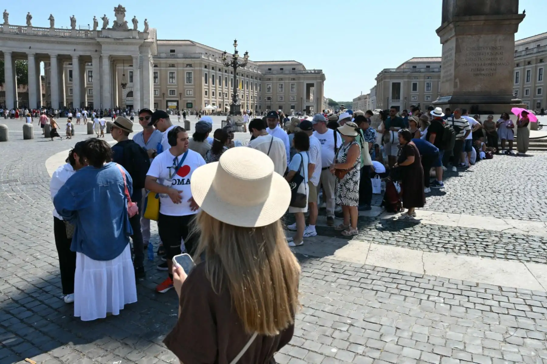 Varias personas hacen cola a la sombra mientras esperan el rezo del Ángelus dominical, oficiado por el Papa León XIV, en la Plaza de San Pedro del Vaticano. Foto: ANDINA/AFP