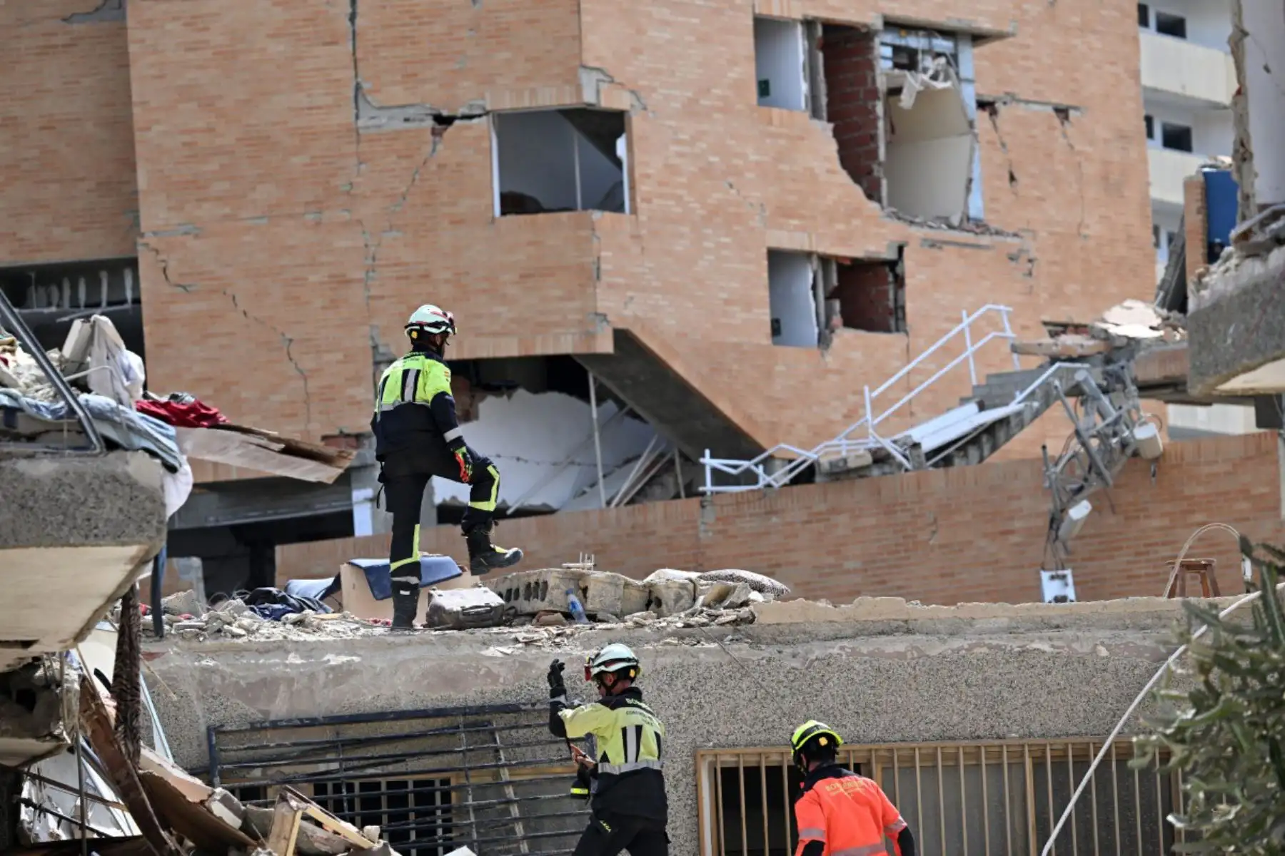 Rescatistas españoles caminan sobre los escombros de un edificio derrumbado en Catia La Mar, estado de La Guaira, Venezuela, tras los terremotos. Miles de rescatistas, familiares y voluntarios excavan día y noche entre montones de concreto para encontrar sobrevivientes de los terremotos que azotaron Venezuela hace más de tres días. 
Foto: ANDINA/AFP