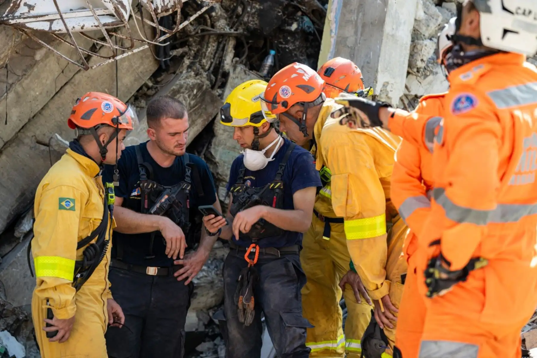 Miembros del 7.º Regimiento de Intervención y Formación en Seguridad Civil intercambian información con equipos de rescate brasileños junto a un edificio dañado en Catia La Mar, estado de La Guaira, Venezuela. Foto: AFP