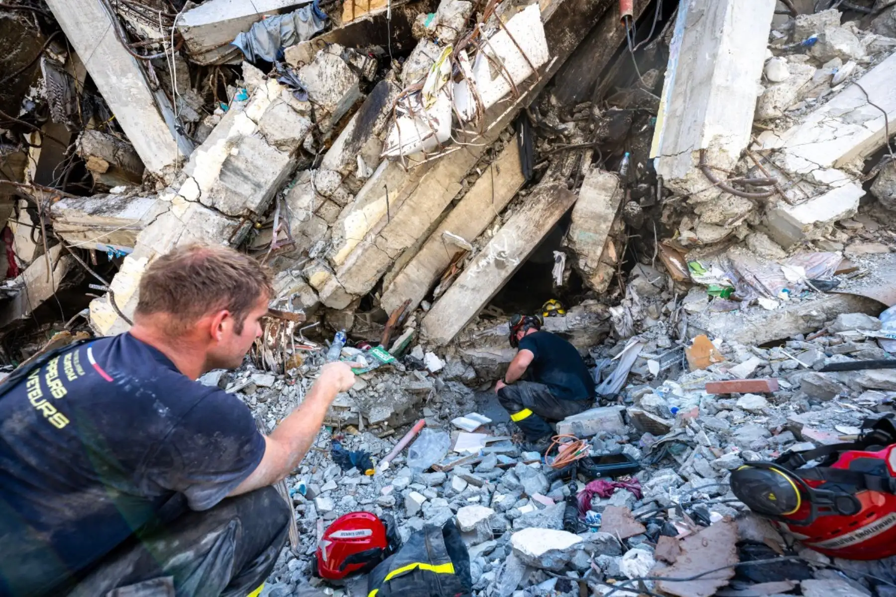 Miembros del 7.º Regimiento de Intervención y Formación en Seguridad Civil intercambian información con equipos de rescate brasileños junto a un edificio dañado en Catia La Mar, estado de La Guaira, Venezuela. Foto: AFP