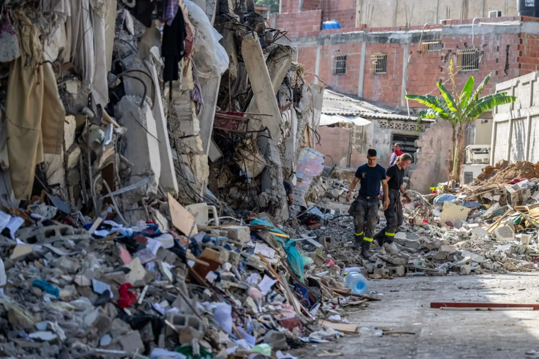Miembros del 7.º Regimiento de Intervención y Formación en Seguridad Civil intercambian información con equipos de rescate brasileños junto a un edificio dañado en Catia La Mar, estado de La Guaira, Venezuela. Foto: AFP