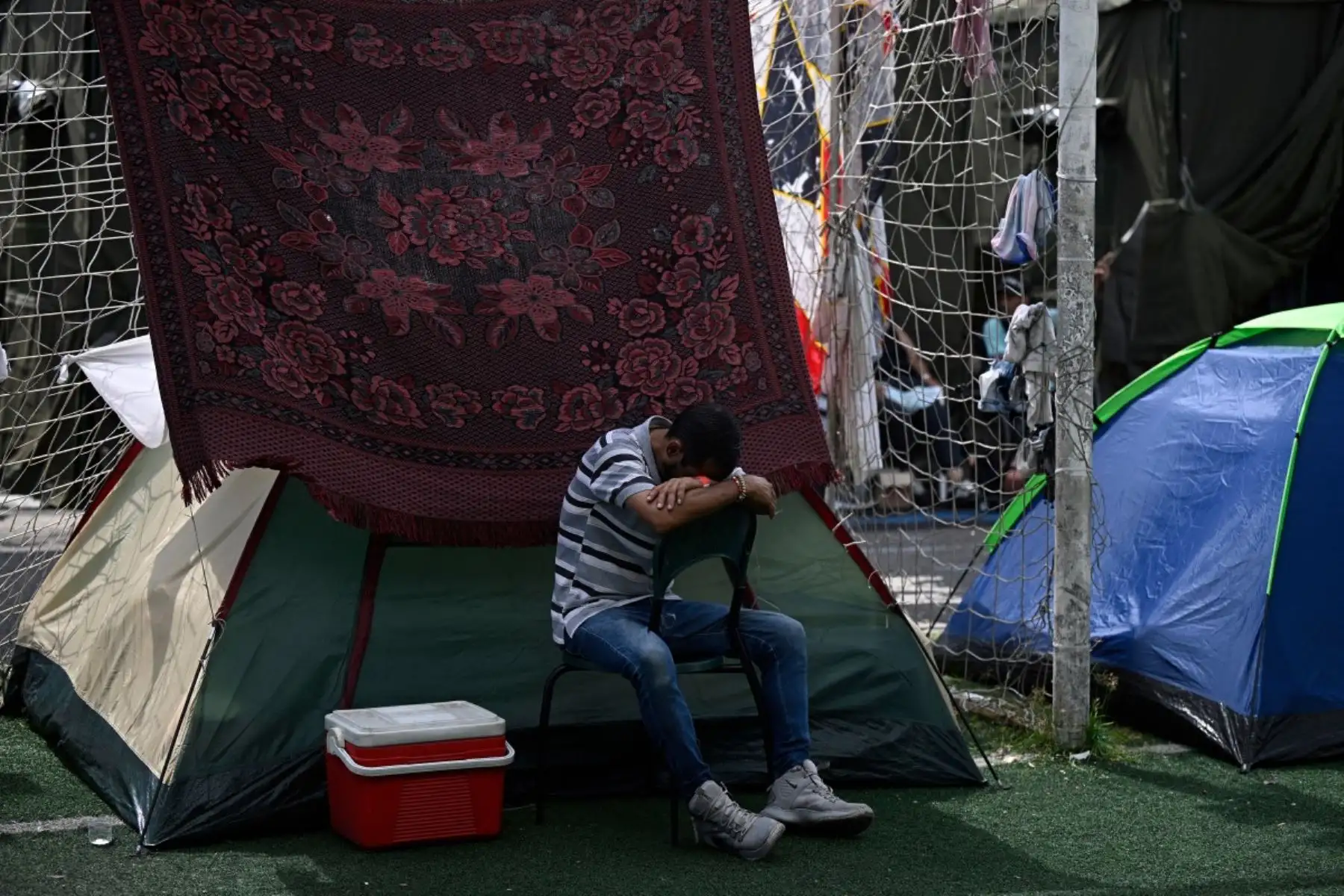 Un hombre desplazado tras los dos terremotos del 24 de junio toma una siesta en una silla en un campamento improvisado en el complejo deportivo José María Vargas en Maiquetía, estado de La Guaira, Venezuela, el 30 de junio de 2026. Foto: AFP