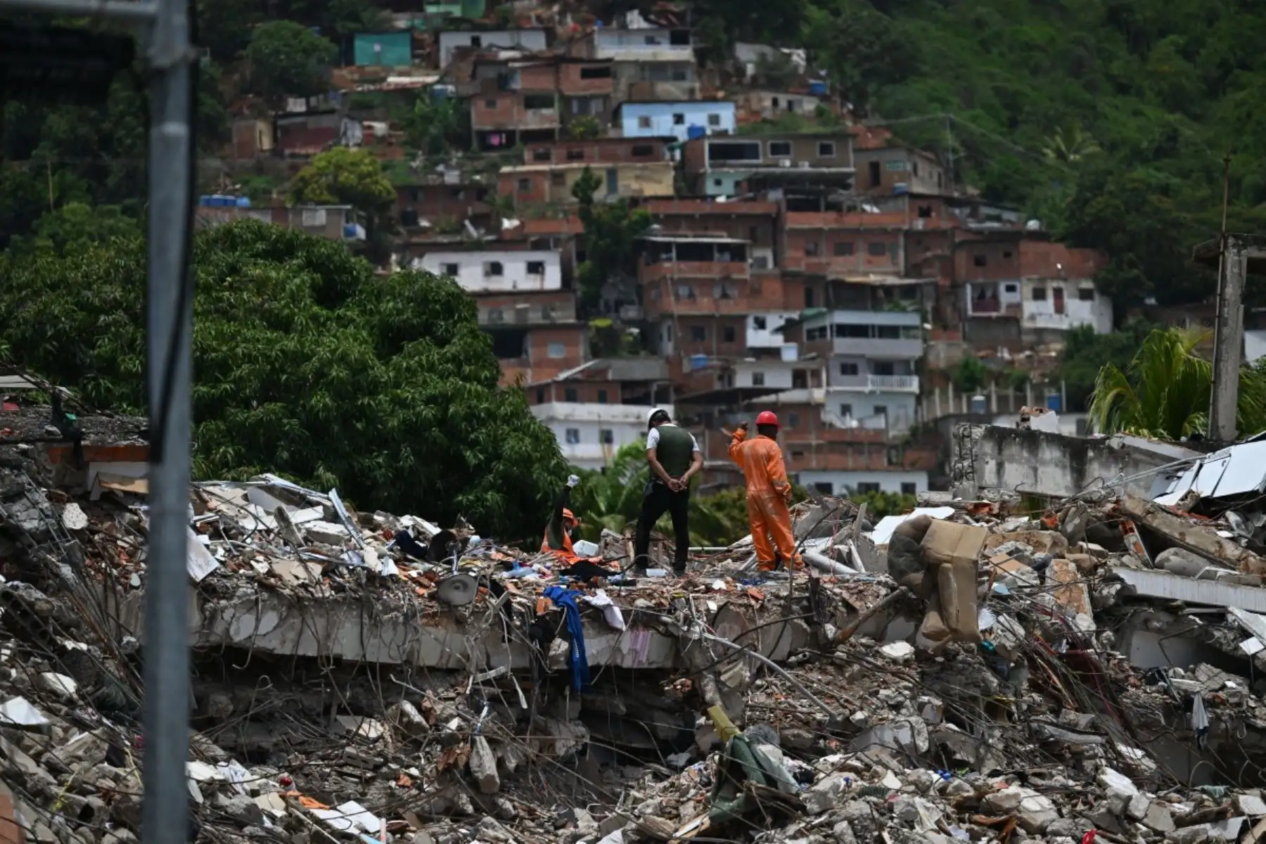 Un rescatista levanta la mano para pedir silencio a la gente mientras intenta encontrar sobrevivientes en un edificio derrumbado tras los dos terremotos del 24 de junio, en Caraballeda, estado de La Guaira, Venezuela, el 30 de junio de 2026. Foto: AFP
