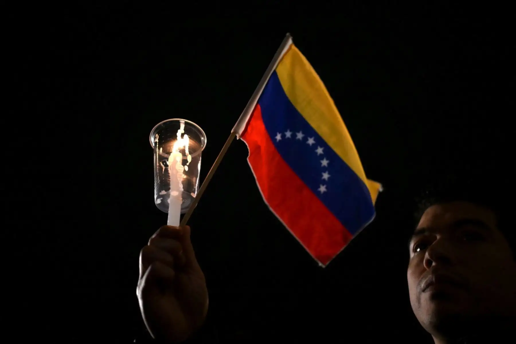 Un hombre sostiene una vela encendida y una bandera venezolana durante una vigilia por las víctimas de los terremotos en Venezuela en la Plaza Estado del Vaticano en Buenos Aires. Foto: AFP