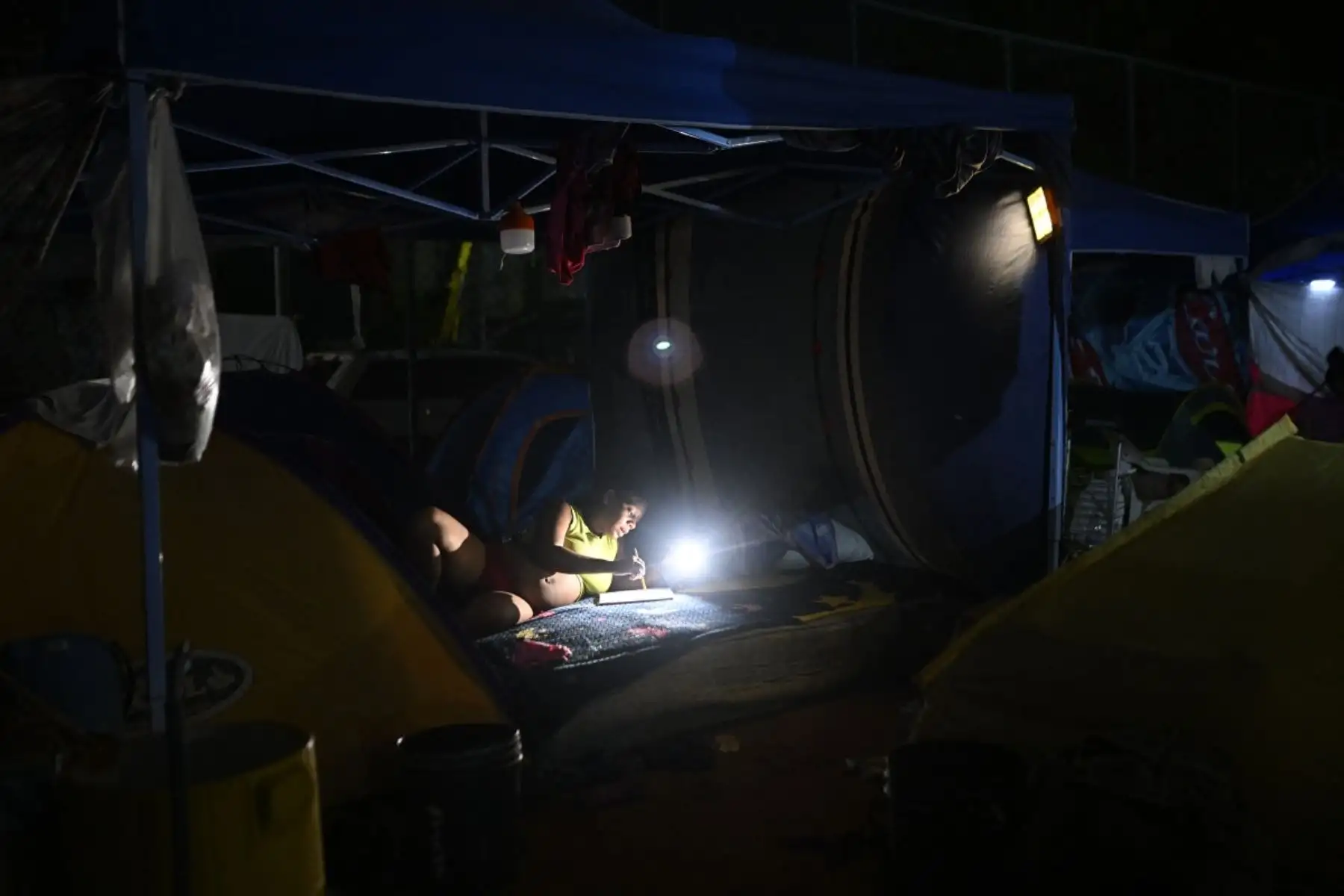 Una mujer desplazada permanece sentada en un campamento improvisado por la noche en Catia La Mar, estado de La Guaira, Venezuela. Foto: AFP