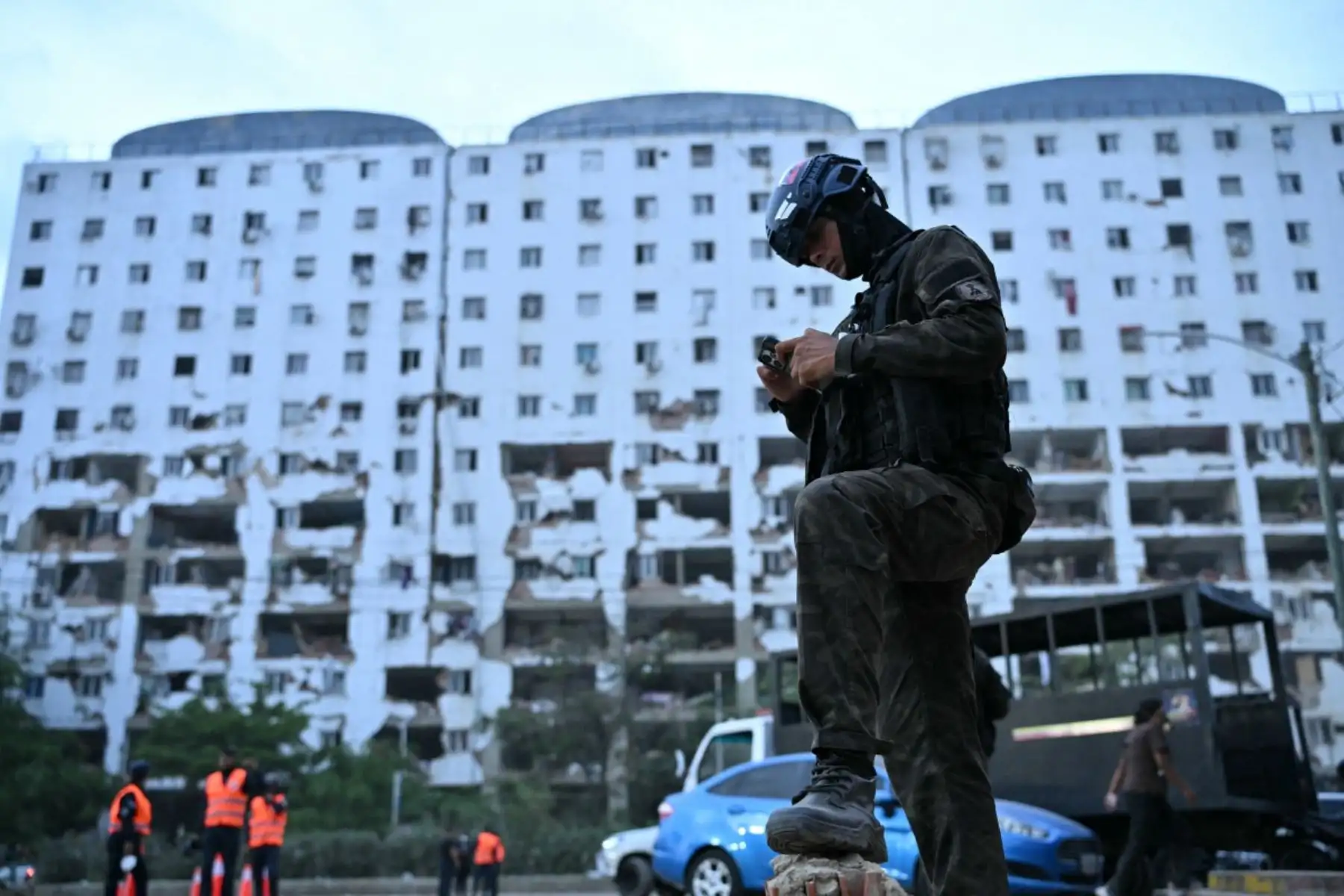 Un agente de policía mira un teléfono móvil frente a un edificio parcialmente derrumbado en Caraballeda, estado de La Guaira, Venezuela, el 3 de julio de 2026. Foto: AFP
