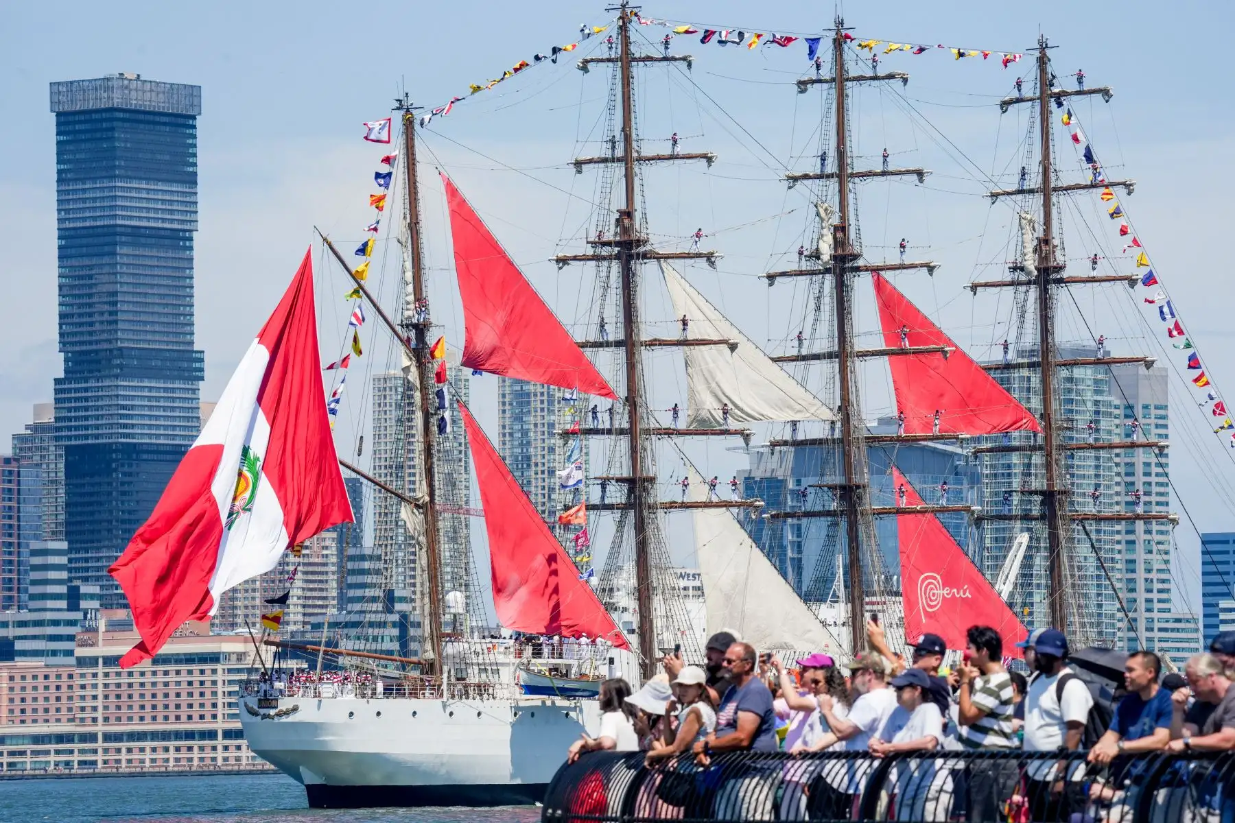 Norteamericanos y turistas observan cómo el Buque Armada Peruana B.A.P. “Unión” navega durante el desfile naval «Sail 4th 250» en el puerto de Nueva York, el 4 de julio de 2026, conmemorando el 250 aniversario del Día de la Independencia de Estados Unidos. Foto: AFP