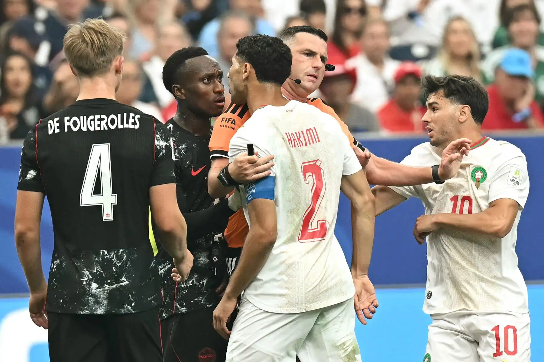 El árbitro inglés Michael Oliver separa al defensa marroquí Achraf Hakimi y al defensa canadiense Richie Laryea mientras discuten junto al delantero marroquí Brahim Díaz durante el partido de octavos de final de la Copa Mundial 2026 entre Canadá y Marruecos, disputado en el Houston Stadium de Houston el 4 de julio. Foto: AFP