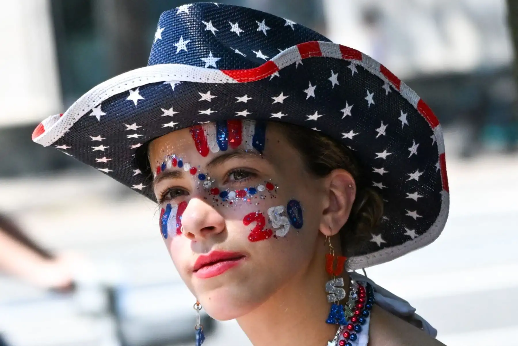 Una mujer luce pintura facial patriótica mientras camina por una calle de Washington, D.C., antes de la celebración del Día de la Independencia "Salute to America" ​​el 4 de julio de 2026. La nación conmemora el 250 aniversario de la Declaración de Independencia de los Estados Unidos. Foto: AFP