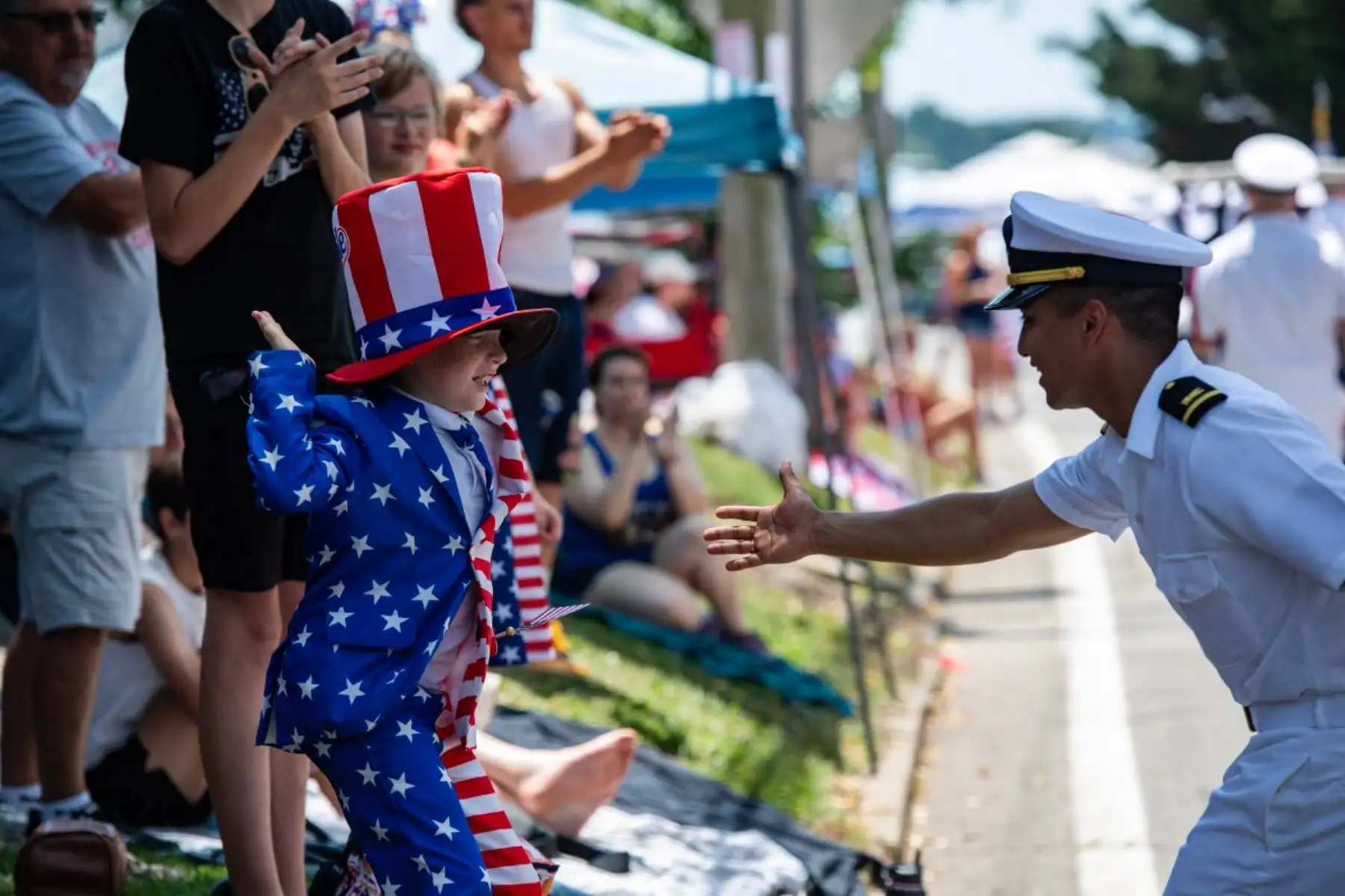 Un niño disfrazado de Tío Sam choca las cinco con un miembro de la Marina de los EE. UU. durante el desfile del 4 de julio en Bristol, Rhode Island, el 4 de julio de 2026. Foto: AFP