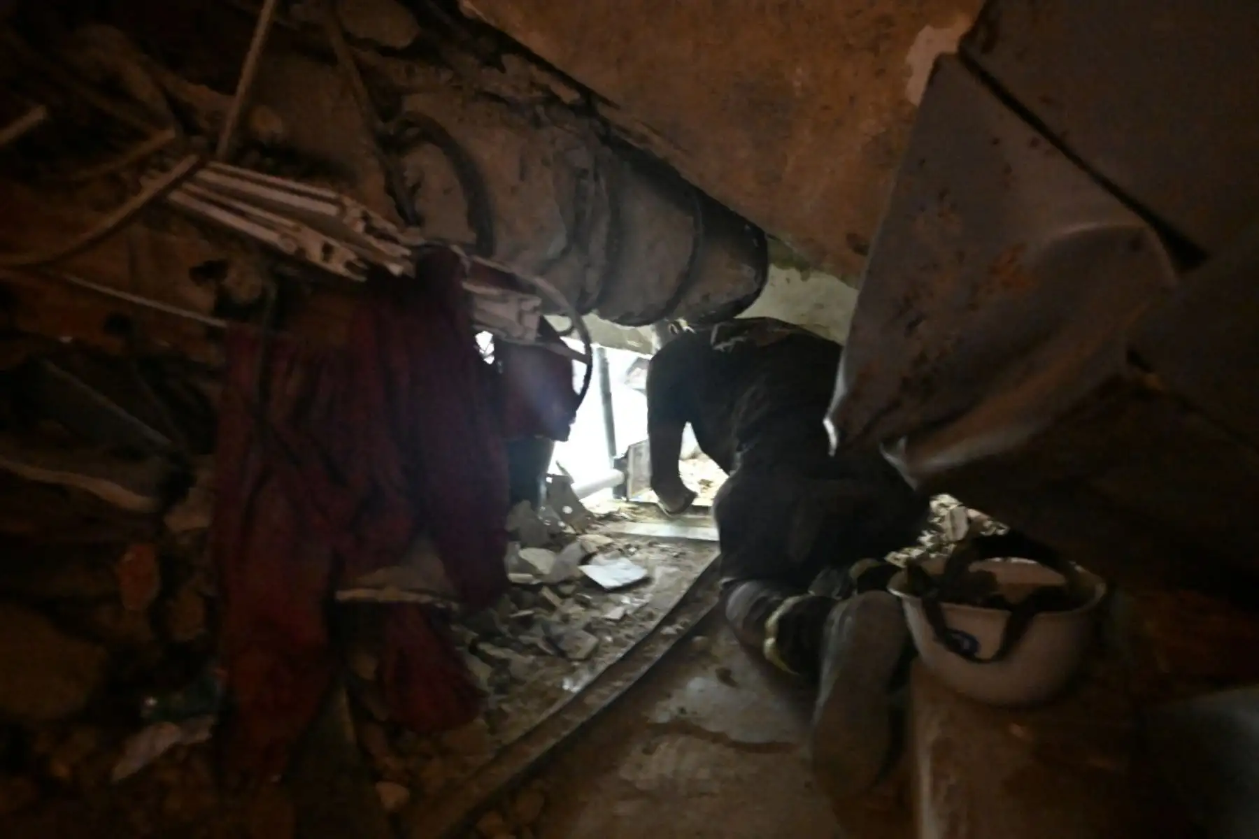 Un rescatista se arrastra por un espacio estrecho entre los escombros de los edificios de la OPPE, un complejo residencial gravemente dañado por los terremotos, en Caraballeda, estado de La Guaira, Venezuela, el 4 de julio de 2026. Foto: AFP