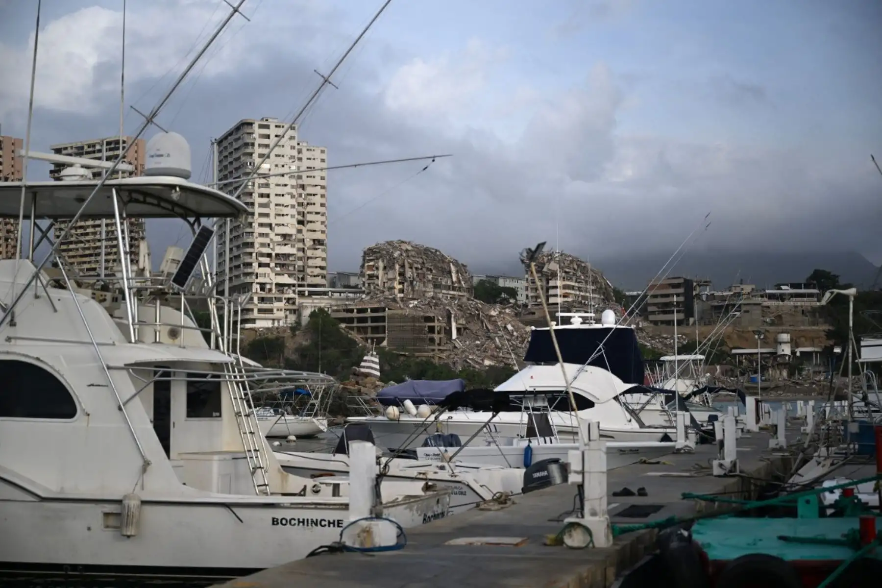 En Catia La Mar, estado de La Guaira, en las afueras de Caracas, el 4 de julio de 2026, tras los dos terremotos del 24 de junio, se observan embarcaciones amarradas en un puerto deportivo, con edificios gravemente dañados y estructuras derrumbadas al fondo. Foto: AFP