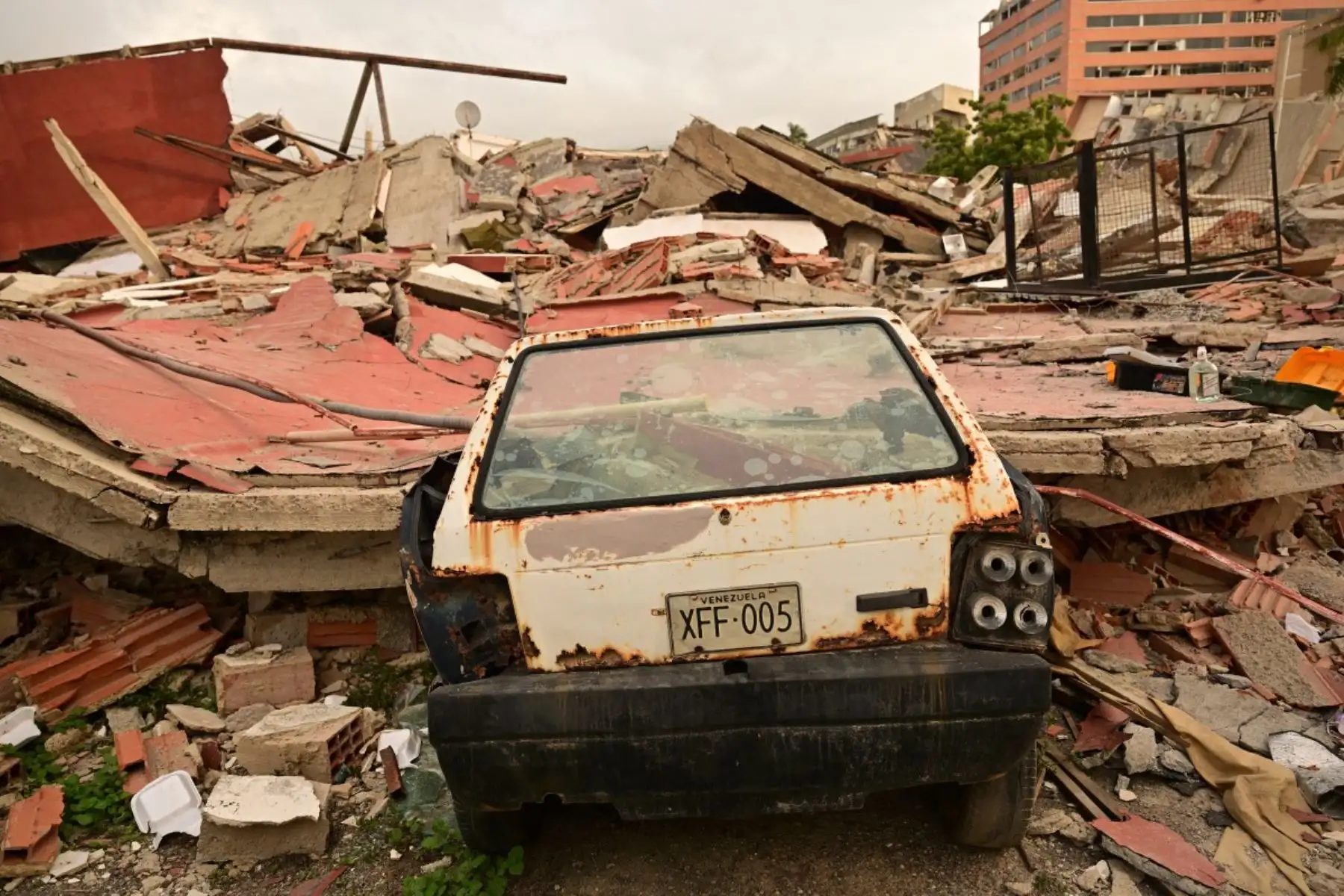 Un automóvil aplastado yace entre los escombros de edificios derrumbados cerca del Hotel Marriott en Playa Grande, estado de La Guaira, en las afueras de Caracas, el 4 de julio de 2026, tras los dos terremotos del 24 de junio. Foto: AFP