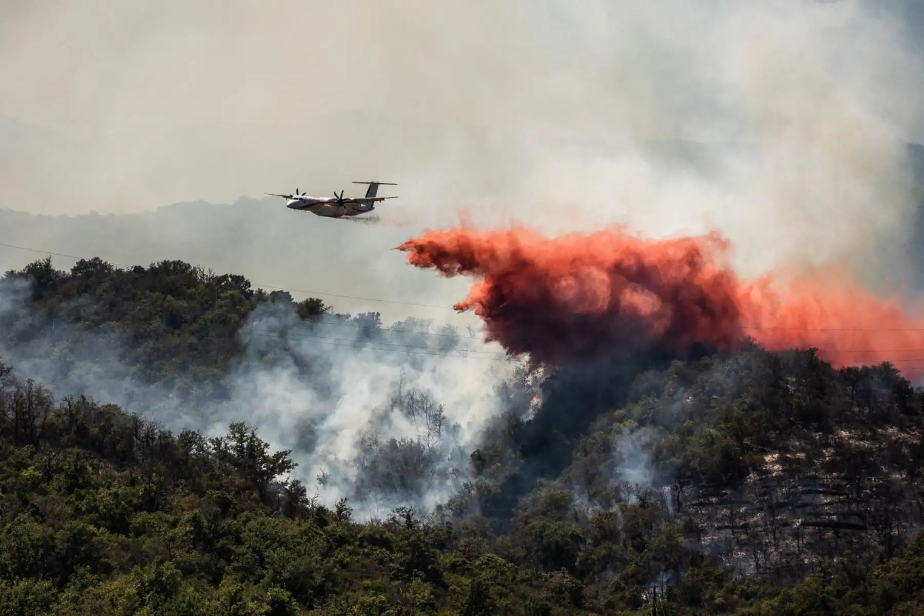 Un avión Dash Q400-MRE Fireguard de la seguridad civil arroja retardante de fuego sobre un incendio forestal que azota el departamento de Pirineos Orientales, en el sur de Francia, donde 700 bomberos, apoyados por aeronaves especiales, luchan por controlar un incendio "gigantesco" que se extiende por una zona remota de difícil acceso, con más de 10.000 residentes locales evacuados, cerca de la ciudad de Bouleternerre, el 6 de julio de 2026. Foto: AFP