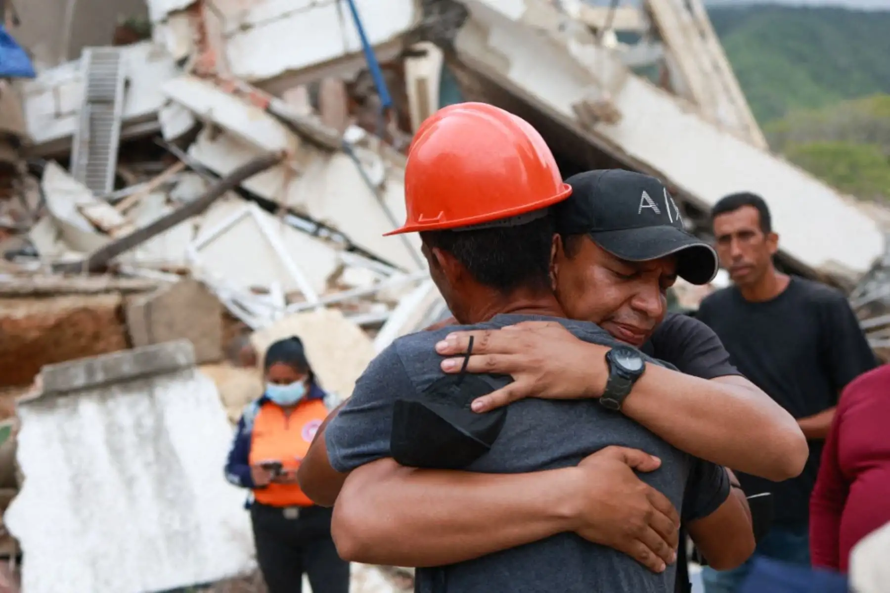 Dos hombres se abrazan tras orar frente a un edificio que colapsó durante el terremoto en La Guaira, Venezuela. Foto: AFP