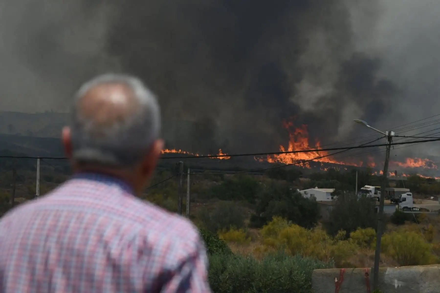 Un hombre observa las llamas cerca de las casas, en la zona afectada por un incendio forestal que dejó 12 muertos cerca de Bedar, en el distrito de Los Gallardos, en la provincia de Almería. Foto: AFP