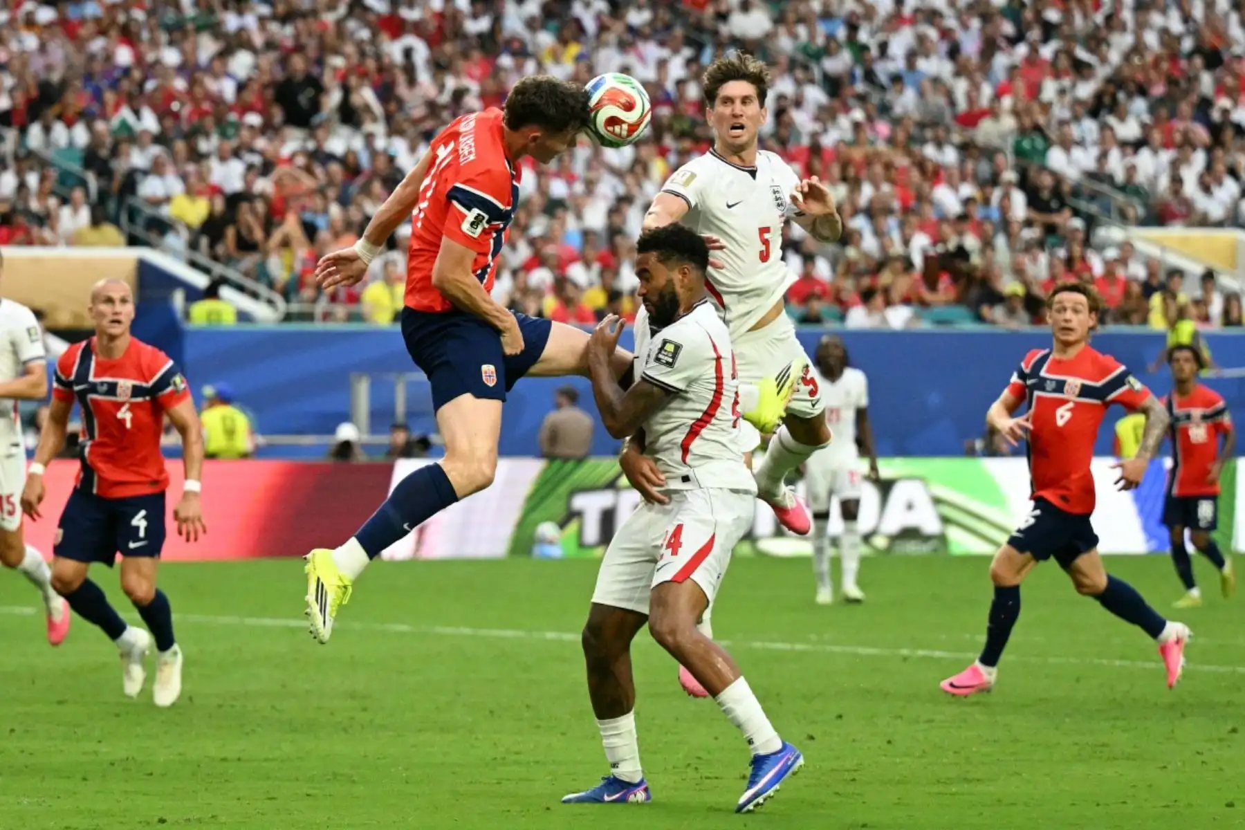 El delantero noruego Jorgen Strand Larsen (izq.), número 11 del ranking, cabecea el balón superando a los defensas ingleses John Stones (número 5) y Reece James (número 24) durante el partido de cuartos de final del Mundial de Fútbol de 2026 entre Noruega e Inglaterra en el Miami Stadium de Miami Gardens el 11 de julio de 2026. (Foto de CHANDAN KHANNA / AFP)