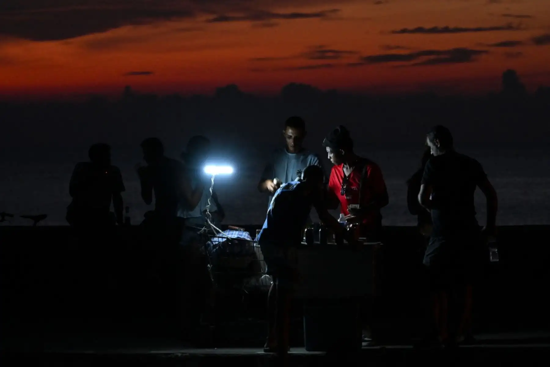 La gente se congrega en el Malecón durante un apagón nacional en La Habana. Cuba sufrió su segundo apagón nacional en cinco días, ya que la doble crisis energética y económica, agravada por un bloqueo de combustible estadounidense de seis meses, provocó el colapso de la red eléctrica. Foto: AFP