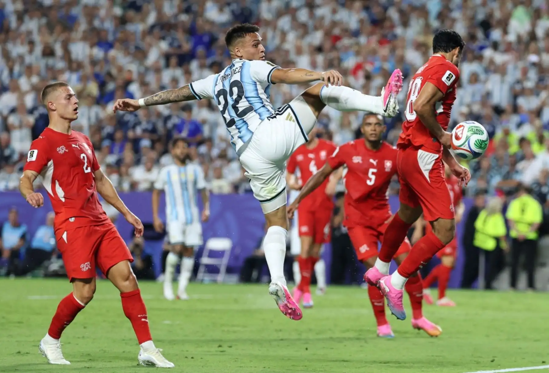 El delantero argentino Lautaro Martínez (número 22) y el defensa suizo Eray Coemert (número 18) luchan por el balón mientras el defensa suizo Miro Muheim (número 2) observa durante el partido de cuartos de final del Mundial de Fútbol de 2026 entre Argentina y Suiza en el Estadio de Kansas City, en Kansas City, el 11 de julio de 2026. (Foto de Thomas COEX / AFP)