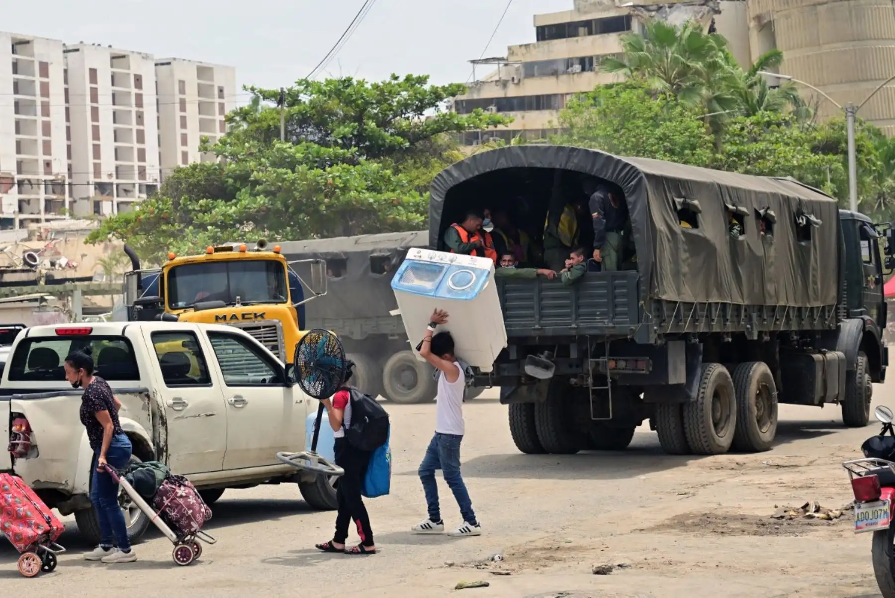 Residentes afectados por los terremotos caminan cargando algunas de sus pertenencias y pasan junto a un camión del ejército, cerca de edificios derrumbados en Caraballeda, estado de La Guaira (Venezuela), el 12 de julio de 2026, tras los dos terremotos que sacudieron la región.
Foto: AFP