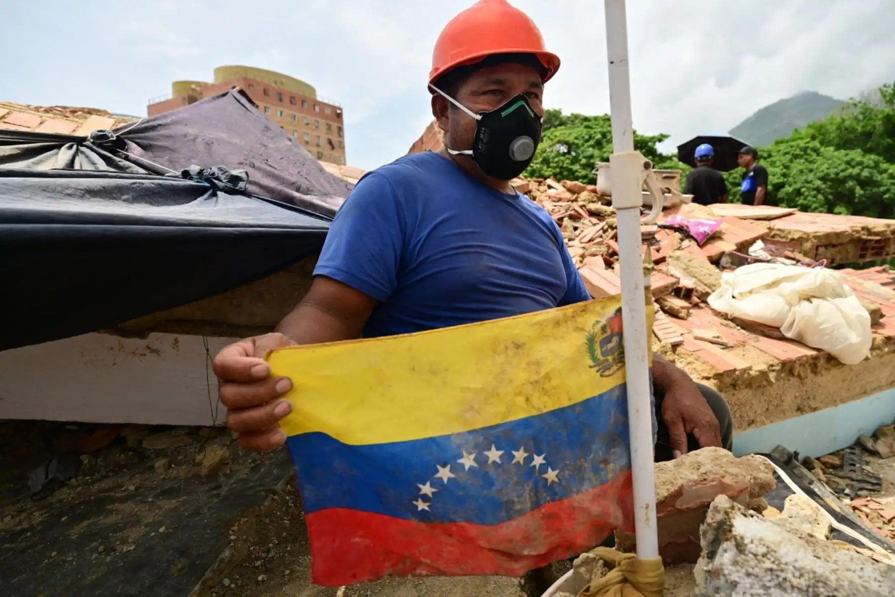 José Miguel González sostiene una bandera de Venezuela en el lugar donde busca los cuerpos de familiares entre los escombros de un edificio colapsado en Caraballeda, estado de La Guaira, Venezuela, el 12 de julio de 2026, tras los dos terremotos que azotaron la región.
La cifra de fallecidos por los dos terremotos que sacudieron Venezuela el 24 de junio ha superado los 4.300, según informó el 11 de julio el presidente de la Asamblea Nacional, Jorge Rodríguez. Foto: AFP