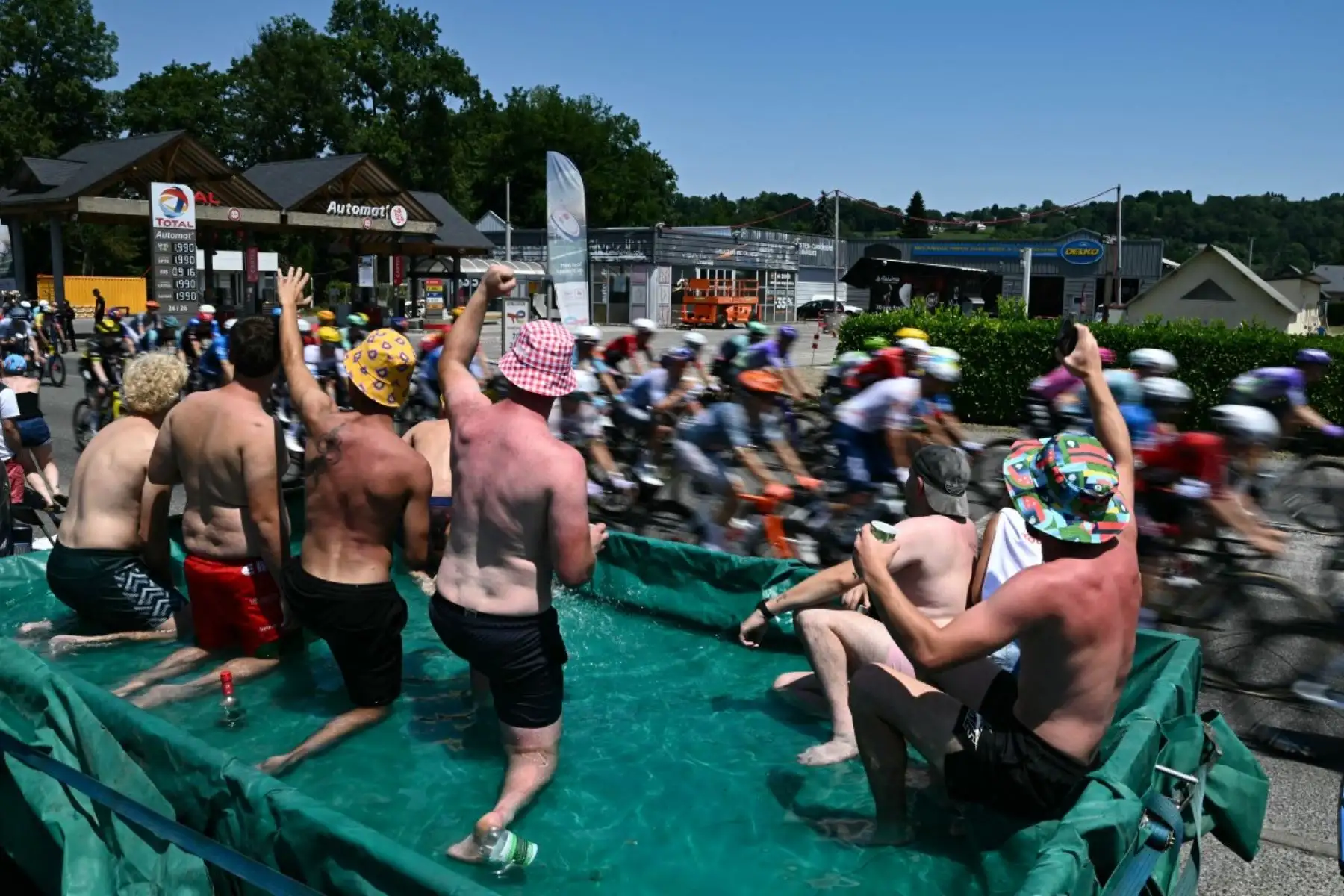Los espectadores animan en una piscina improvisada en un remolque a lo largo del recorrido de la carrera mientras el pelotón de ciclistas pasa durante la sexta etapa de la 113.ª edición del Tour de Francia, de 186,2 km entre Pau y Gavarnie-Gèdre, en los Pirineos franceses, el 9 de julio de 2026. (Foto de Jeff PACHOUD / AFP)