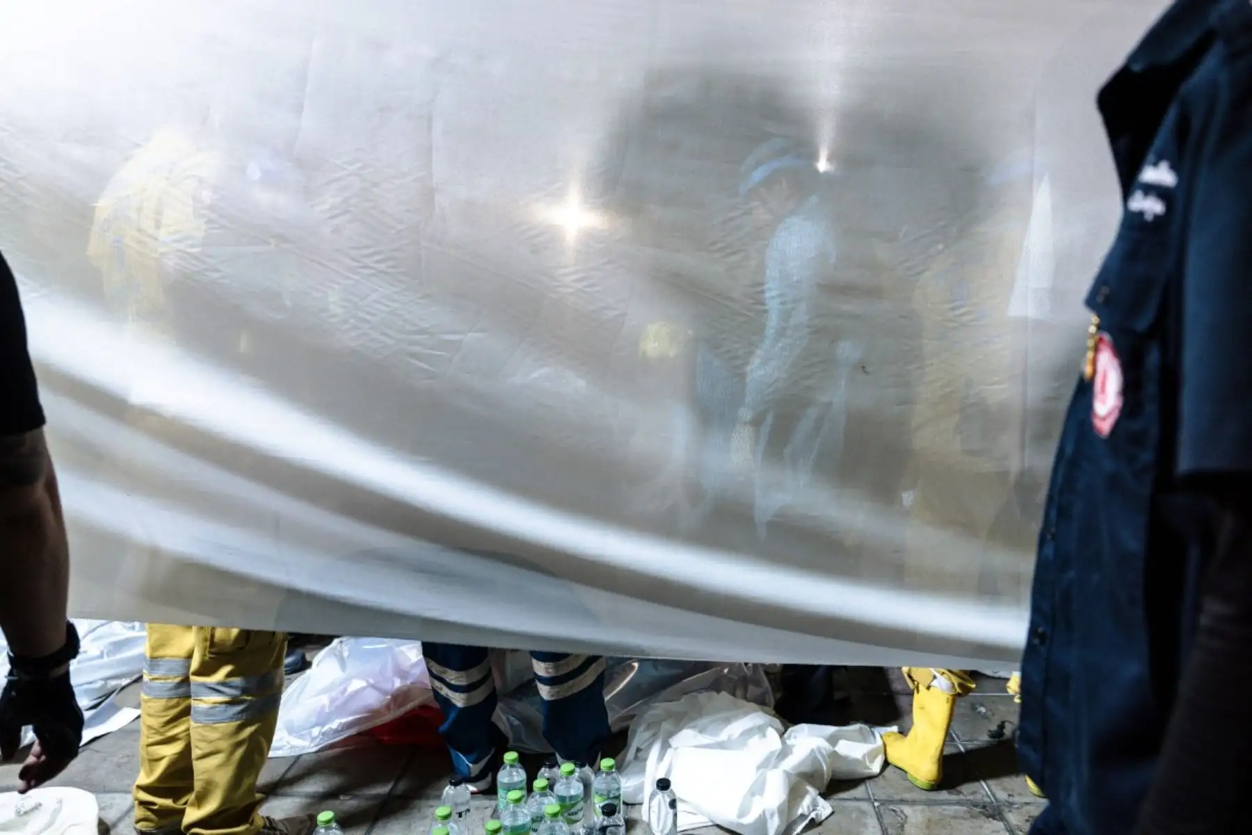 Personal de emergencia se encuentra junto a una tela blanca colocada en el lugar tras el incendio masivo que arrasó un bar en Bangkok, en la madrugada del 13 de julio de 2026. Foto: AFP