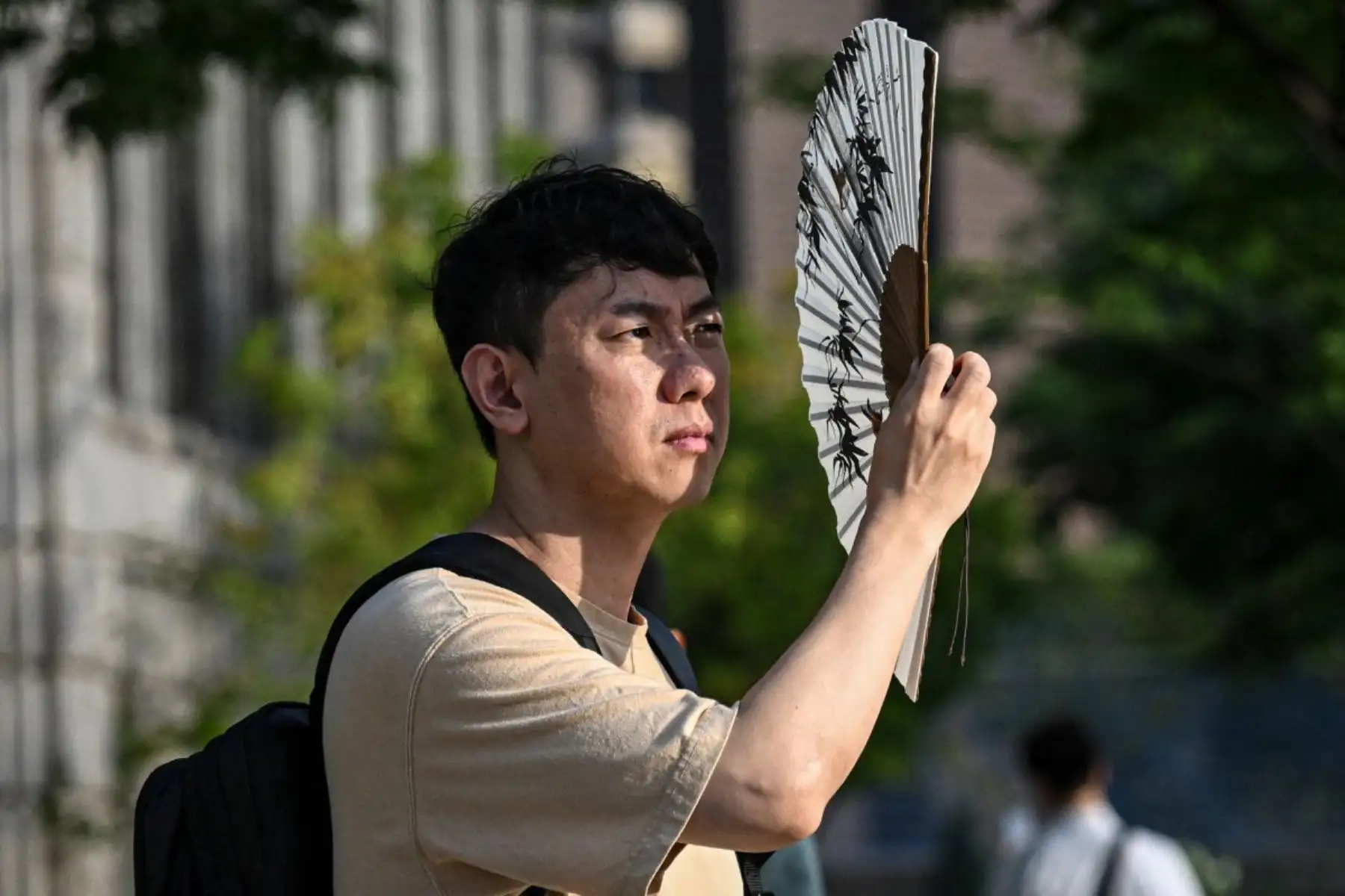 Un hombre se protege del sol con un ventilador en Seúl. Foto: AFP