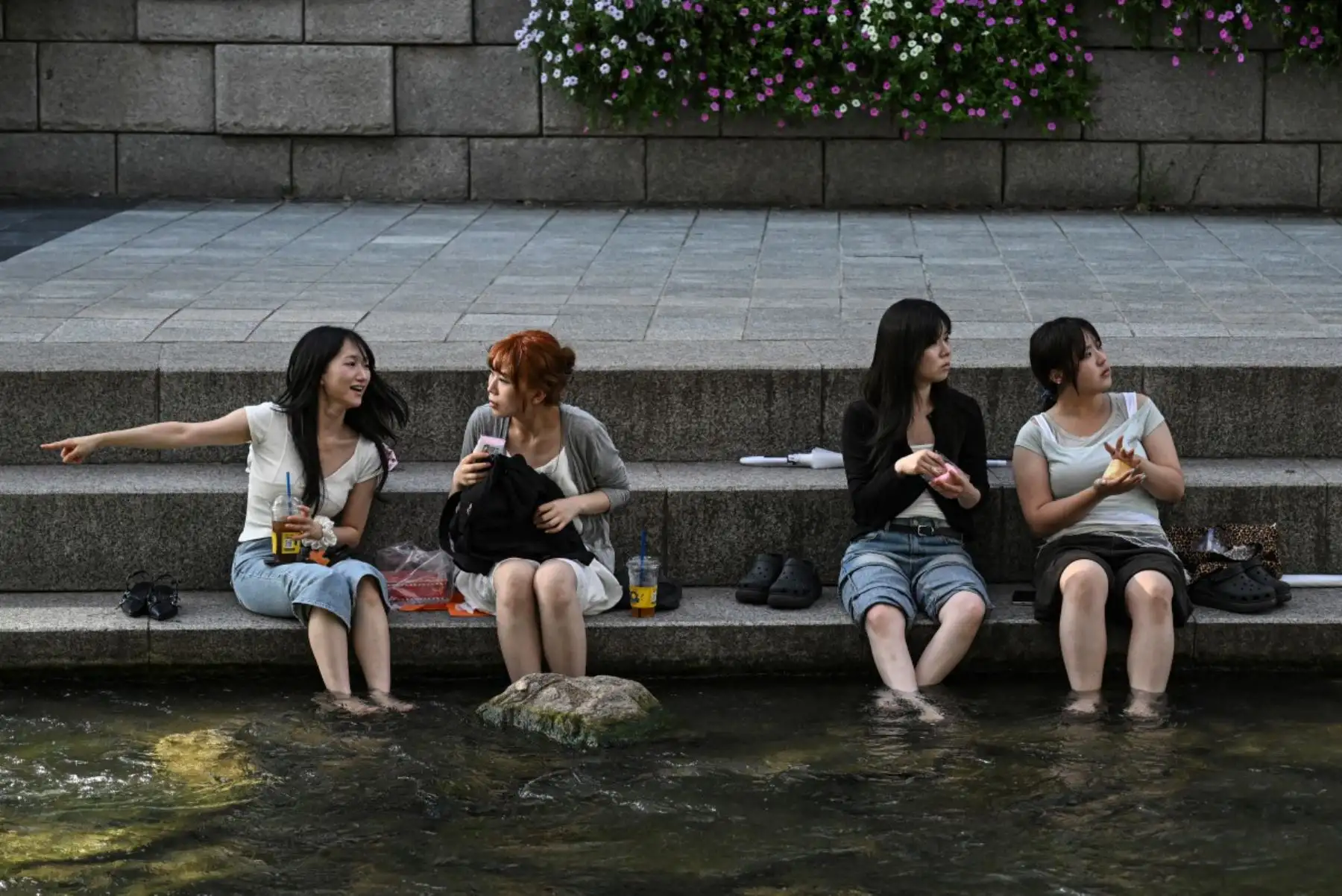 Varias personas se refrescan en el arroyo Cheonggyecheon de Seúl. Foto: AFP
