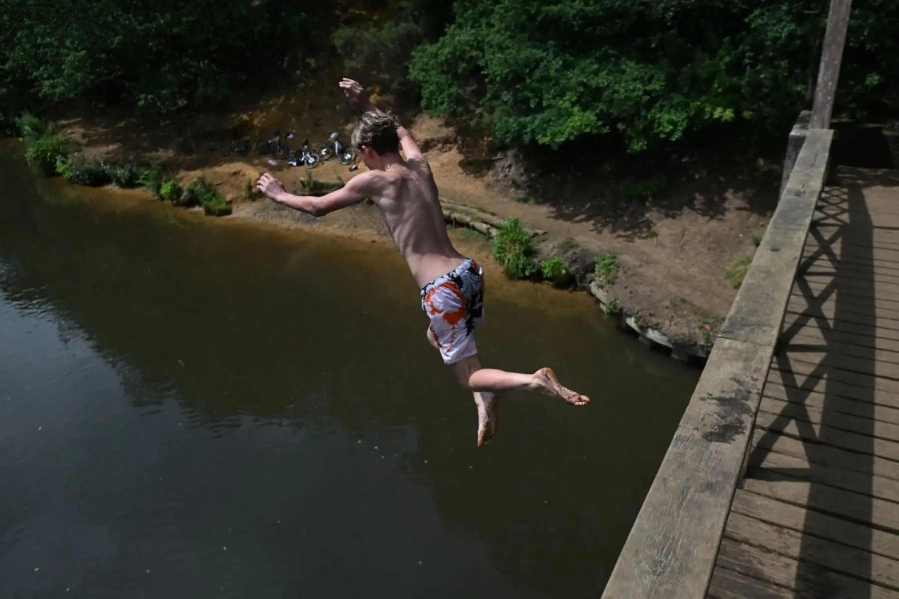 Un joven se refresca saltando desde el puente peatonal de Wey al río Wey, cerca de Guildford, al sur de Londres. Foto: AFP