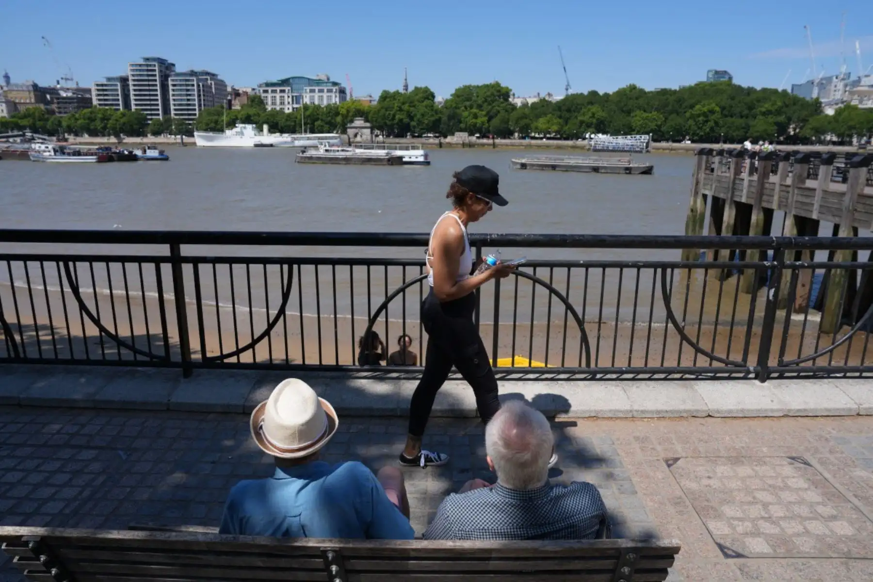 Varias personas se sientan a la sombra de un árbol mientras contemplan el río Támesis, en el centro de Londres. Foto: AFP