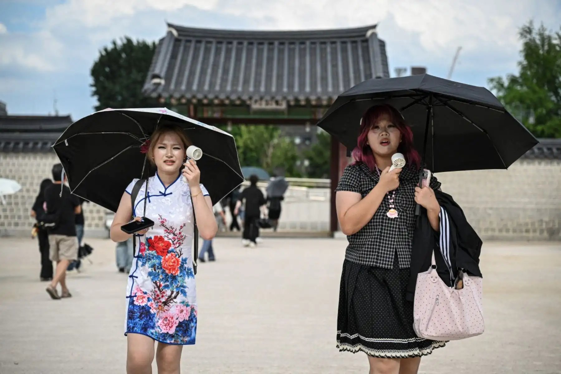 Mujeres usan ventiladores portátiles para refrescarse en el Palacio Gyeongbokgung en Seúl. Foto: AFP
