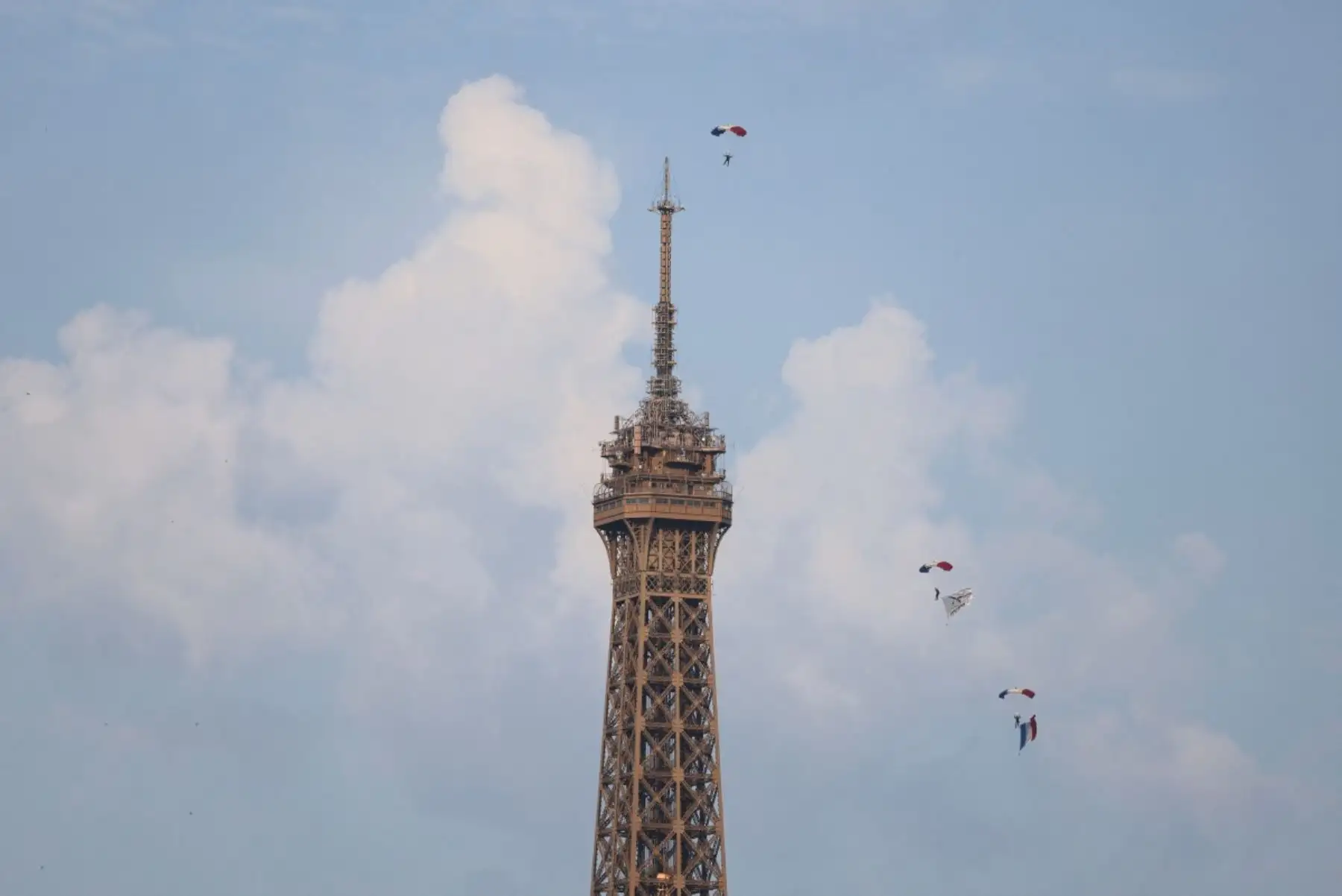 Paracaidistas del Ejército del Aire y del Espacio francés despliegan una bandera nacional francesa en el aire junto a la Torre Eiffel antes del desfile militar anual del Día de la Bastilla en París. Foto: AFP