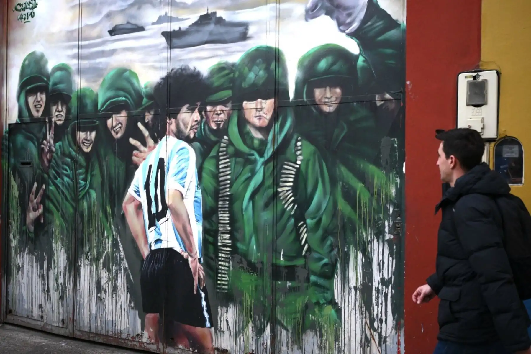 Un hombre pasa junto a un mural que representa al fallecido legendario futbolista argentino Diego Maradona y a soldados argentinos en la Guerra de las Malvinas, en Buenos Aires, el 14 de julio de 2026. Foto: AFP