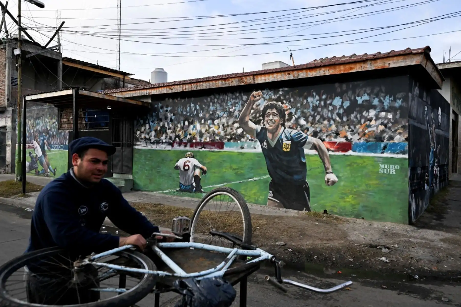 Un hombre aparece junto a un mural que representa al fallecido legendario futbolista argentino Diego Maradona durante el partido del Mundial de México 1986 contra Inglaterra, en Villa Fiorito, en las afueras de Buenos Aires, el 14 de julio de 2026. Foto: AFP