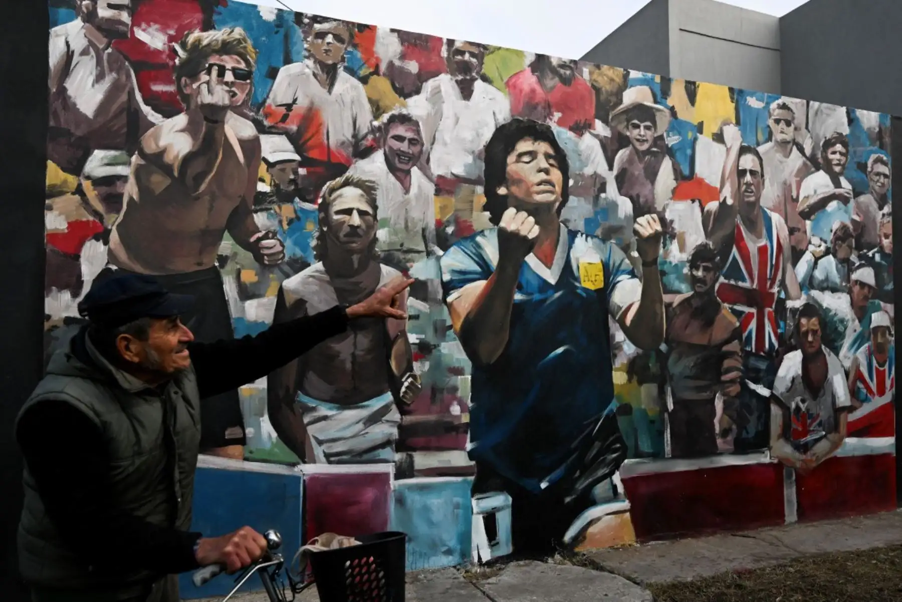 Un hombre señala un mural que representa al fallecido legendario futbolista argentino Diego Maradona durante el partido del Mundial de México 1986 contra Inglaterra, en Villa Fiorito, en las afueras de Buenos Aires, el 14 de julio de 2026. Foto: AFP