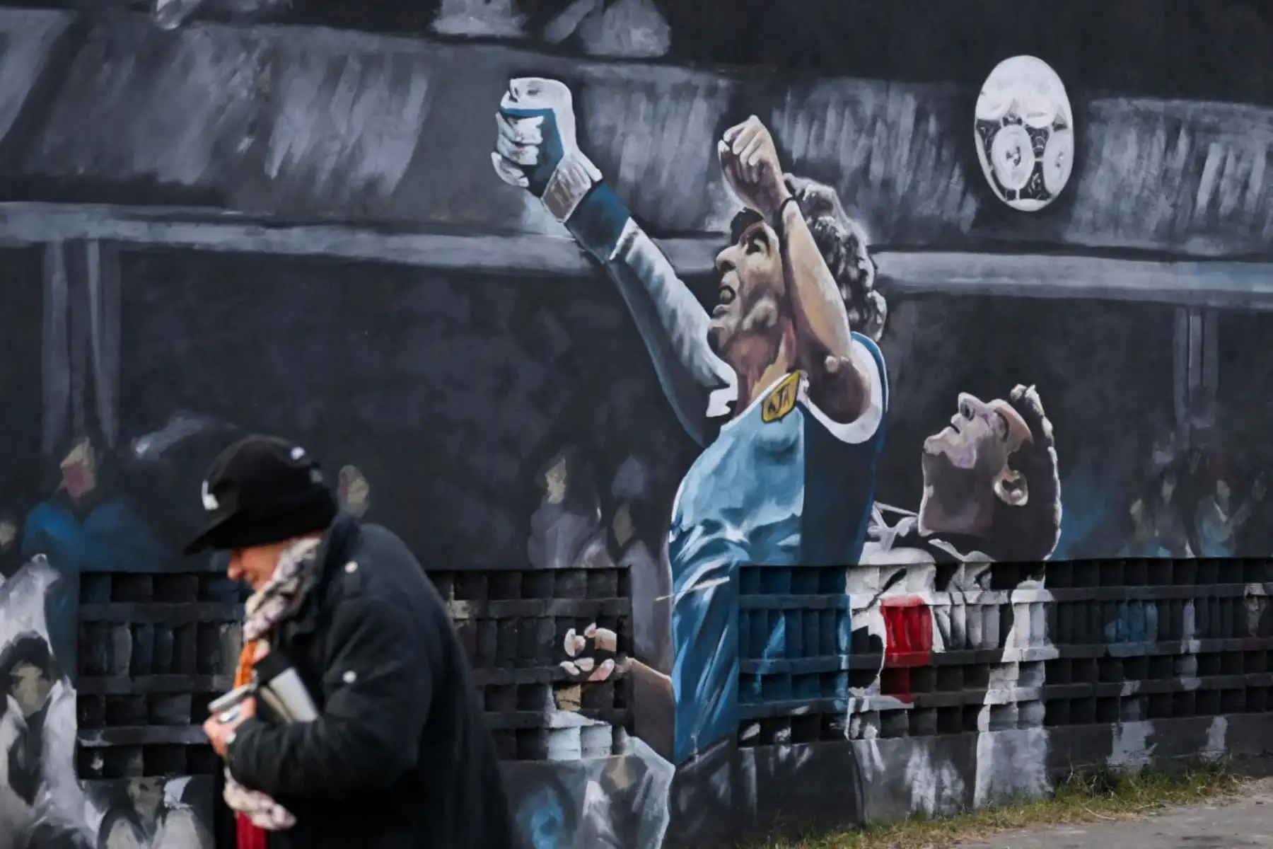 Un hombre pasa junto a un mural que representa al fallecido legendario futbolista argentino Diego Maradona durante el partido del Mundial de México 1986 contra Inglaterra, en Villa Fiorito, en las afueras de Buenos Aires, el 14 de julio de 2026. Foto: AFP