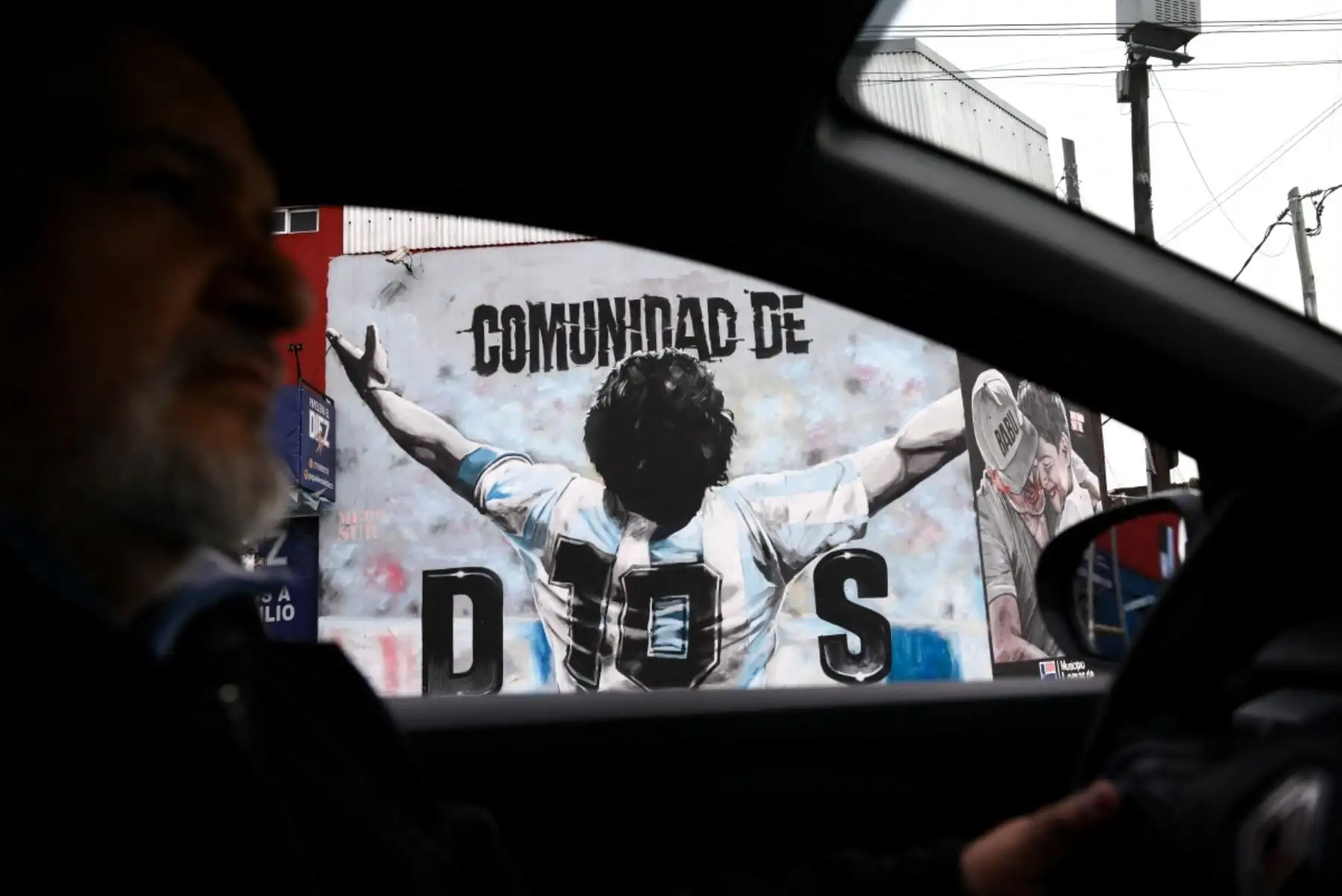 Vista de un mural que representa al fallecido legendario futbolista argentino Diego Maradona desde el interior de un automóvil en Villa Fiorito, en las afueras de Buenos Aires, el 14 de julio de 2026. Foto: AFP