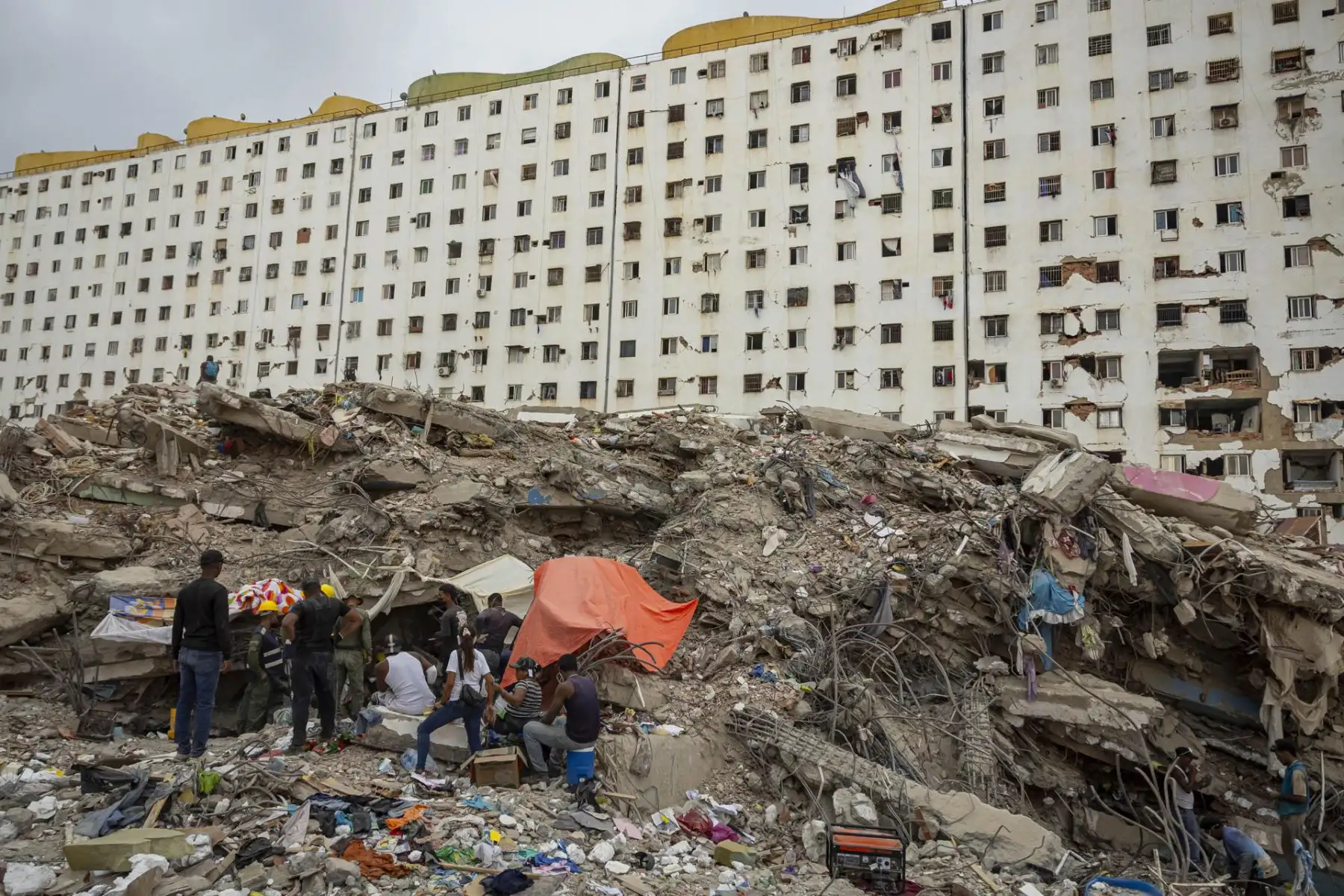 Personas instalan campamentos frente a edificios destruidos por terremotos este viernes, en Caraballeda (Venezuela). La cifra de muertos por el doble terremoto del pasado 24 de junio en Venezuela ascendió a 5.069, tras sumarse 139 nuevos fallecimientos, informó el presidente del Parlamento, Jorge Rodríguez, quien también detalló que la cantidad de heridos se mantiene en 16.740. Foto: EFE