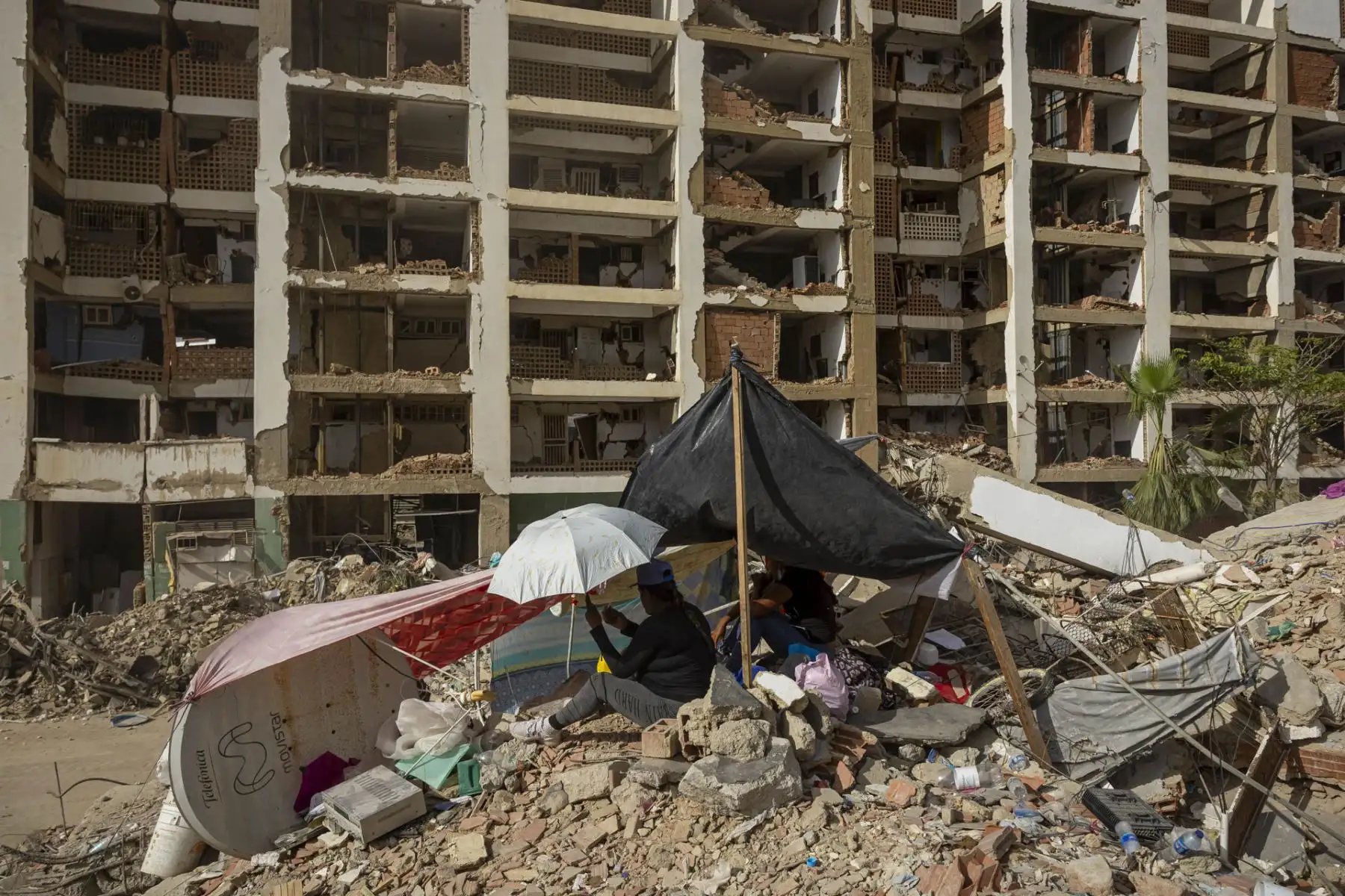 Personas instalan campamentos frente a edificios destruidos por terremotos este viernes, en Caraballeda (Venezuela). La cifra de muertos por el doble terremoto del pasado 24 de junio en Venezuela ascendió a 5.069, tras sumarse 139 nuevos fallecimientos, informó el presidente del Parlamento, Jorge Rodríguez, quien también detalló que la cantidad de heridos se mantiene en 16.740. Foto: EFE