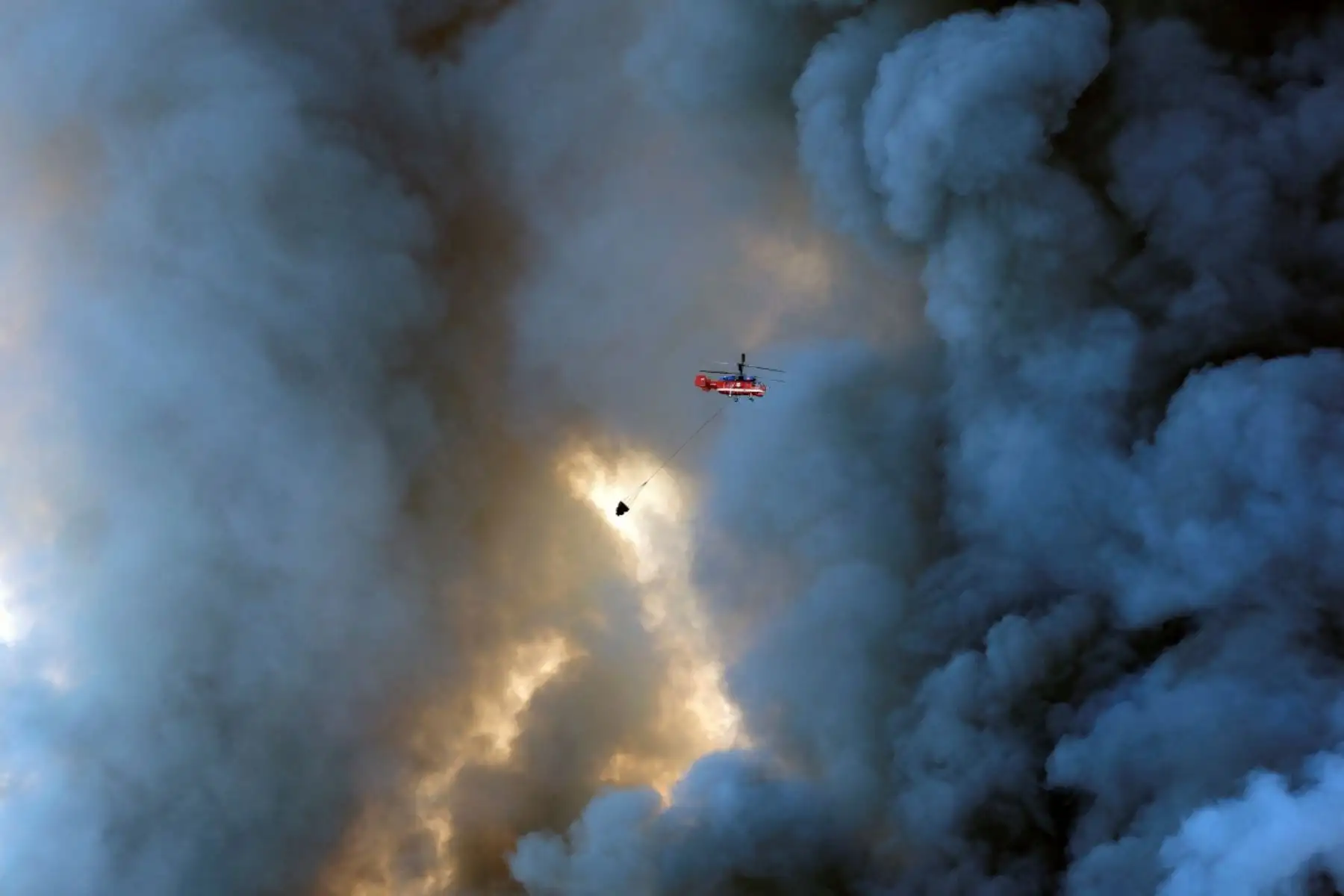 Un helicóptero de extinción de incendios intenta sofocar un fuego en los complejos logísticos de la empresa rusa de comercio electrónico Wildberries, en la localidad de Elektrostal (a las afueras de Moscú), el 18 de julio de 2026.
Un ataque con drones ucranianos contra dos centros logísticos en Rusia causó la muerte de ocho personas y dejó 24 heridas, según informaron las autoridades el 18 de julio de 2026, jornada en la que la región de Moscú reportó una nueva oleada de ataques con drones. La empresa rusa de comercio electrónico Wildberries comunicó que sus complejos logísticos en Kotovsk y Elektrostal —situados en las regiones de Tambov y Moscú, respectivamente— fueron objeto de ataques. Una persona falleció y 37 resultaron heridas en el almacén de Elektrostal, según declaró el gobernador de la región, Andréi Vorobiov. fotoAFP