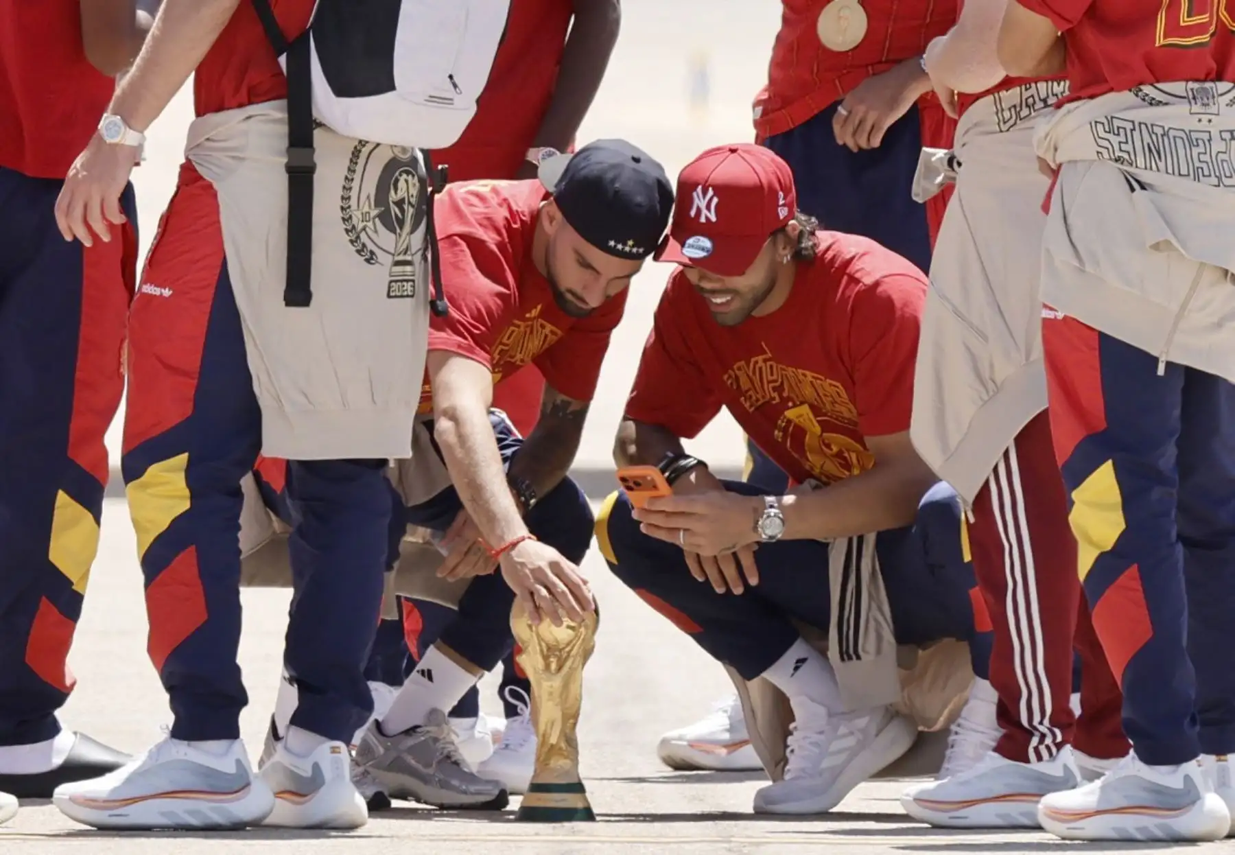 El centrocampista español Álex Baena toca el trofeo en la pista tras la llegada del equipo desde Estados Unidos después de ganar la Copa del Mundo de 2026, en el aeropuerto de Madrid-Barajas. Foto: AFP