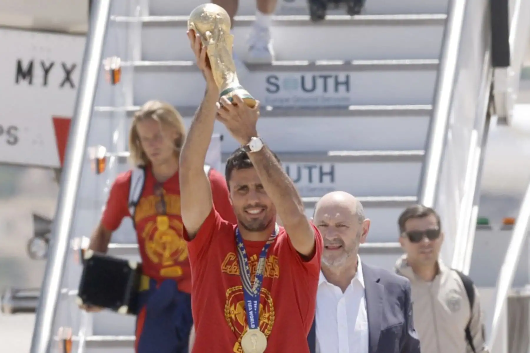 El seleccionador de la selección española de fútbol, ​​Luis de la Fuente, el centrocampista Rodri  y el presidente de la Federación Española de Fútbol, ​​Rafael Louzán, posan con el trofeo a su llegada desde Estados Unidos tras ganar la Copa del Mundo de 2026. Foto: AFP