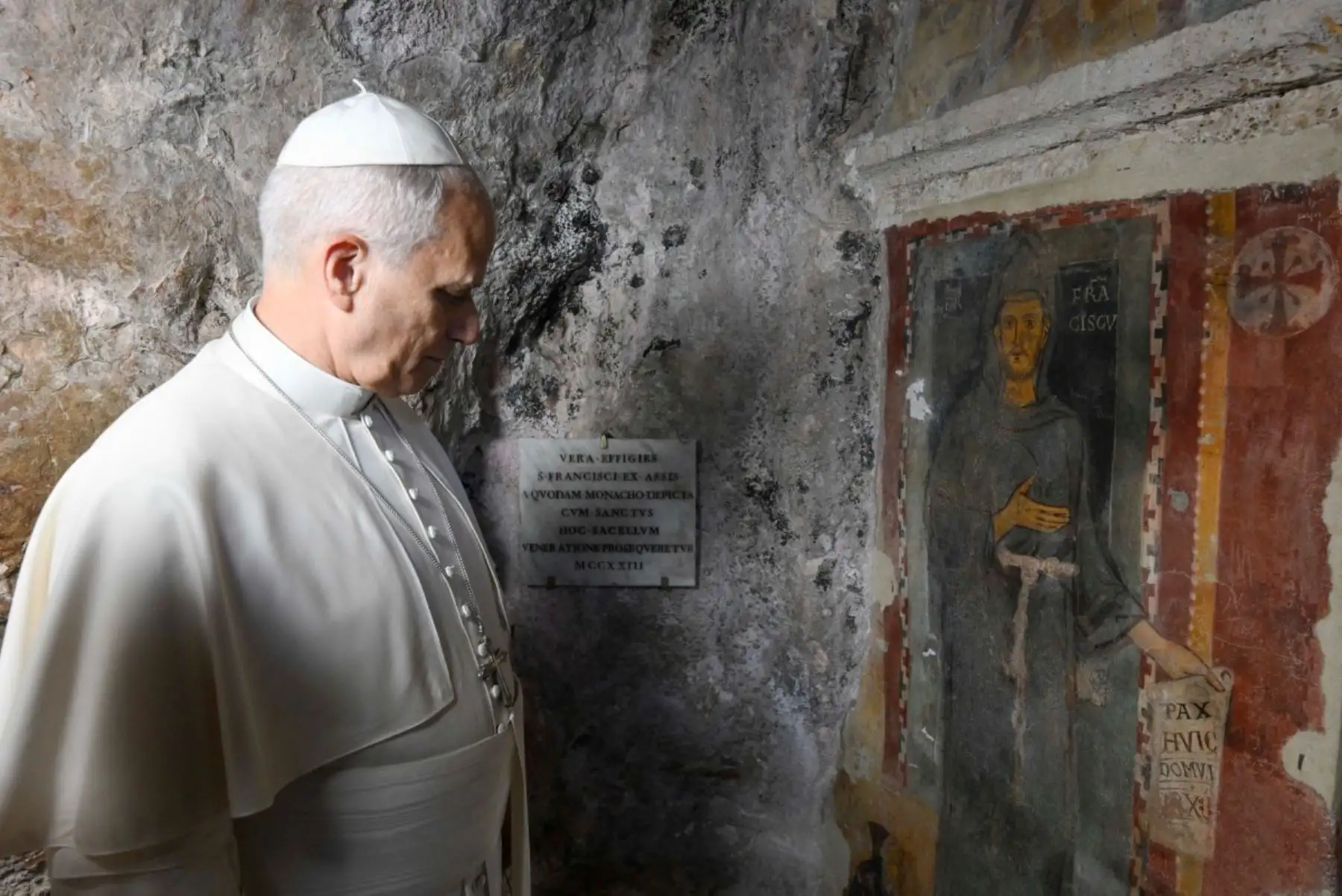 apa León XIV observa un fresco que representa a san Francisco en la gruta de san Benito, situada en el monasterio de San Benito en Subiaco, en el centro de Italia. Foto: AFP