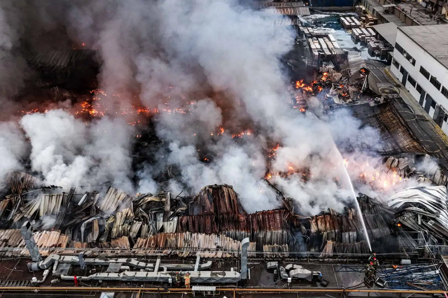 Las llamas comprometen gran parte de las instalaciones de la planta de Yobel, mientras los bomberos ejecutan acciones para evitar la propagación del fuego a inmuebles vecinos. Foto: ANDINA/ Juan Carlos Guzmán