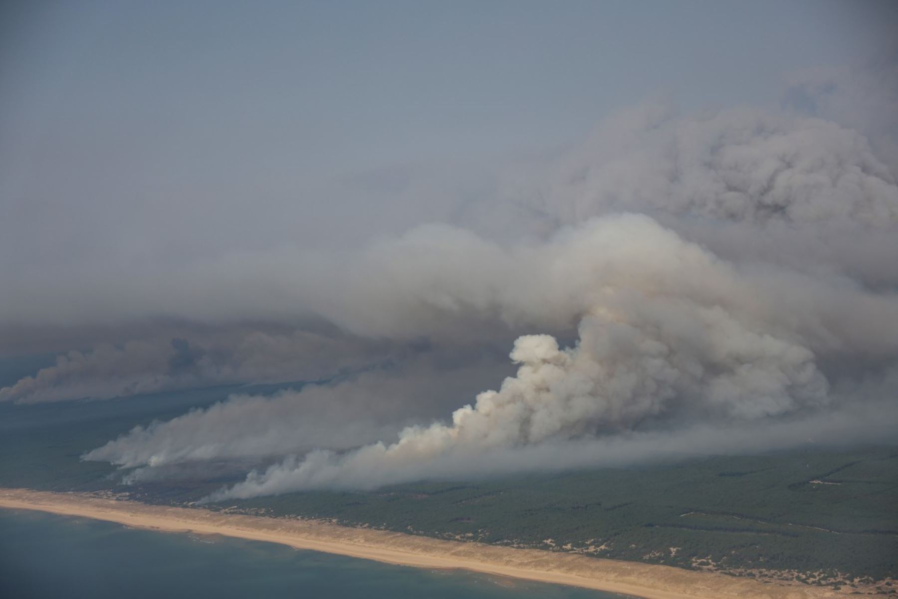 Esta fotografía aérea muestra el humo que emana del incendio forestal al norte de la cuenca de Arcachon, cubriendo el bosque, con una vista de una playa y el océano Atlántico cerca de Lege-Cap-Ferret, en el suroeste de Francia, el 24 de julio de 2026. Foto: AFP